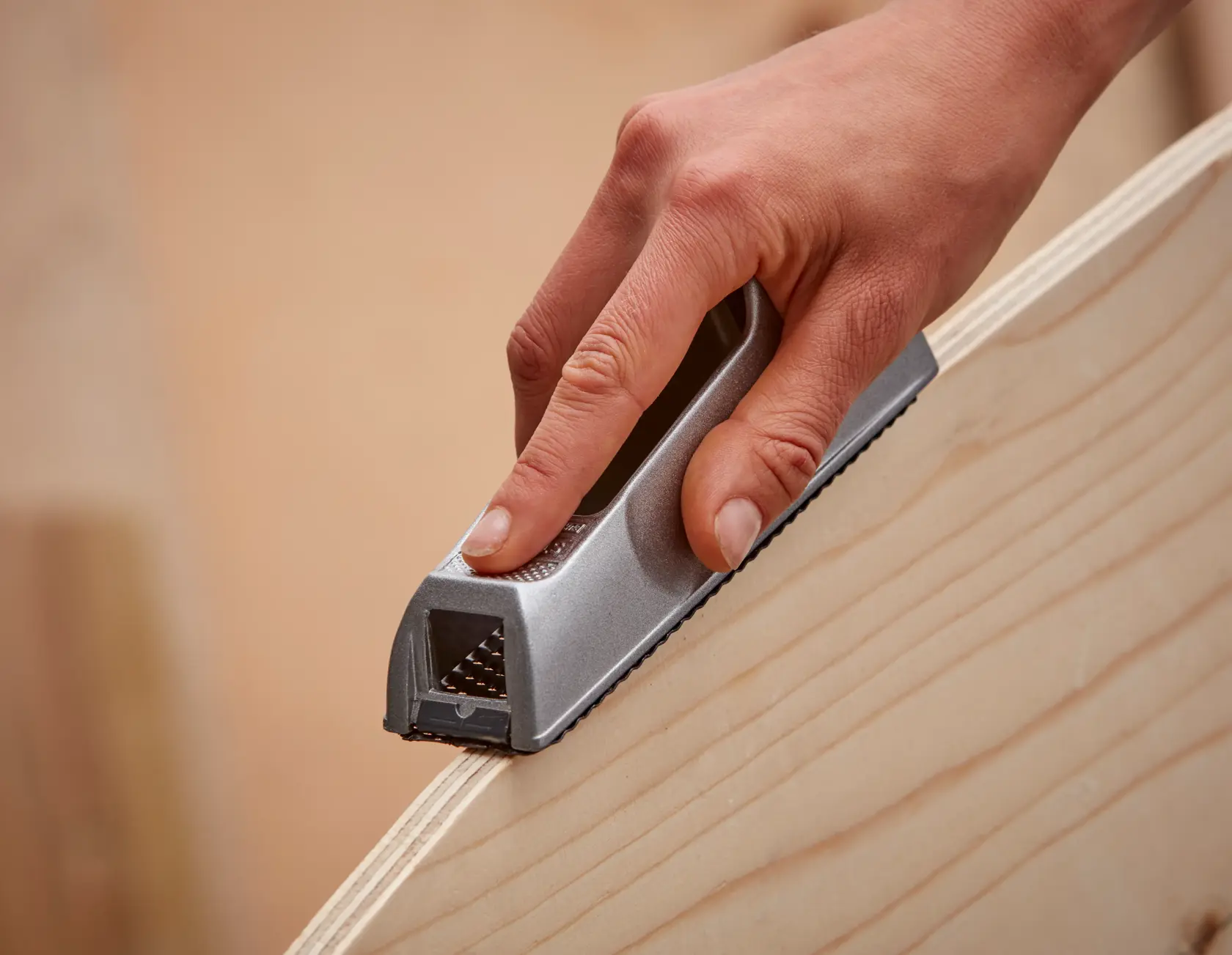 Fotografía del cepillo manual STANLEY 5-21-399 alisando el borde de una madera, vista de cerca.