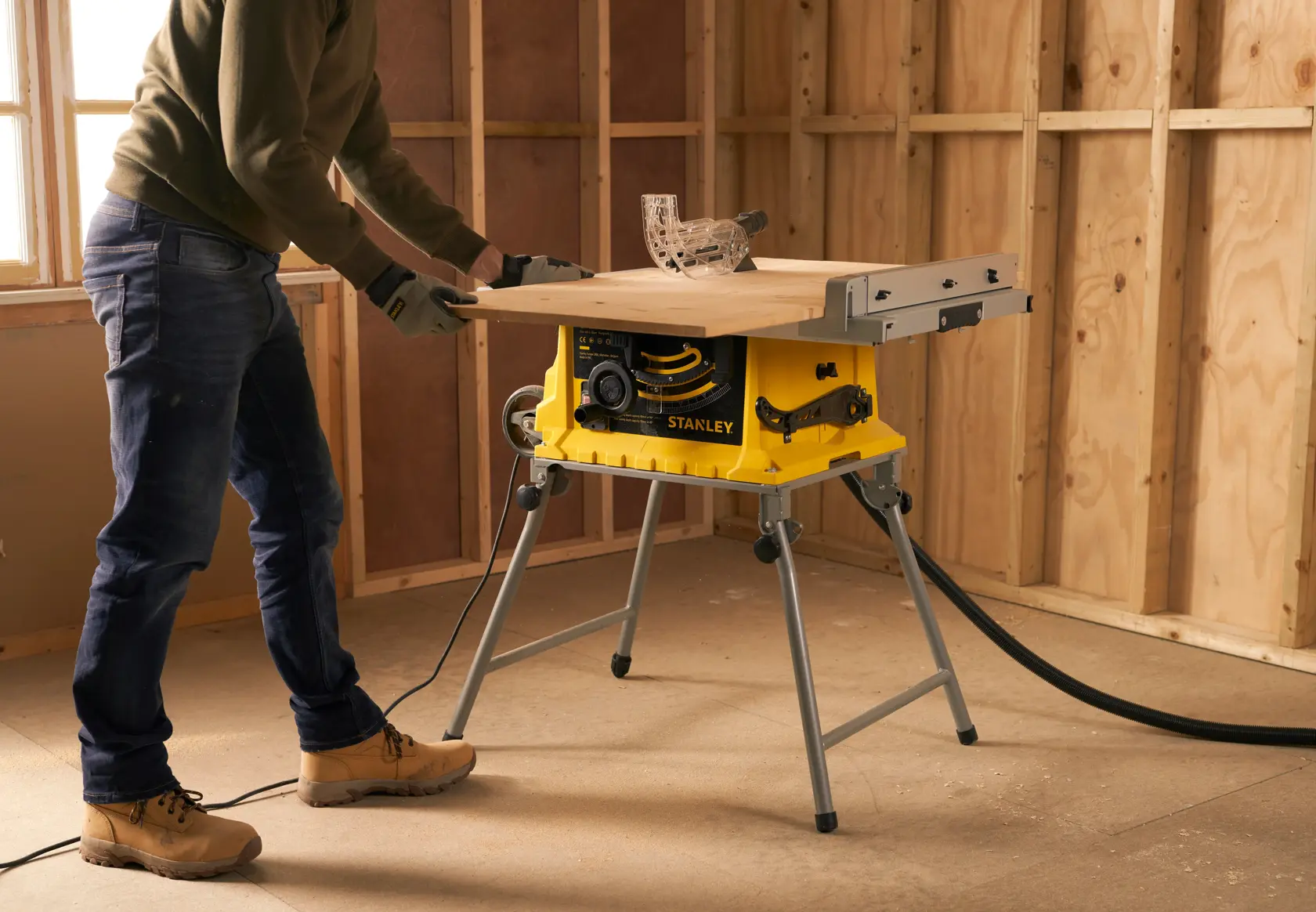 Sierra de banco STANLEY SST1800 en uso en obra, base amarilla, superficie de trabajo extendida, corte de madera.