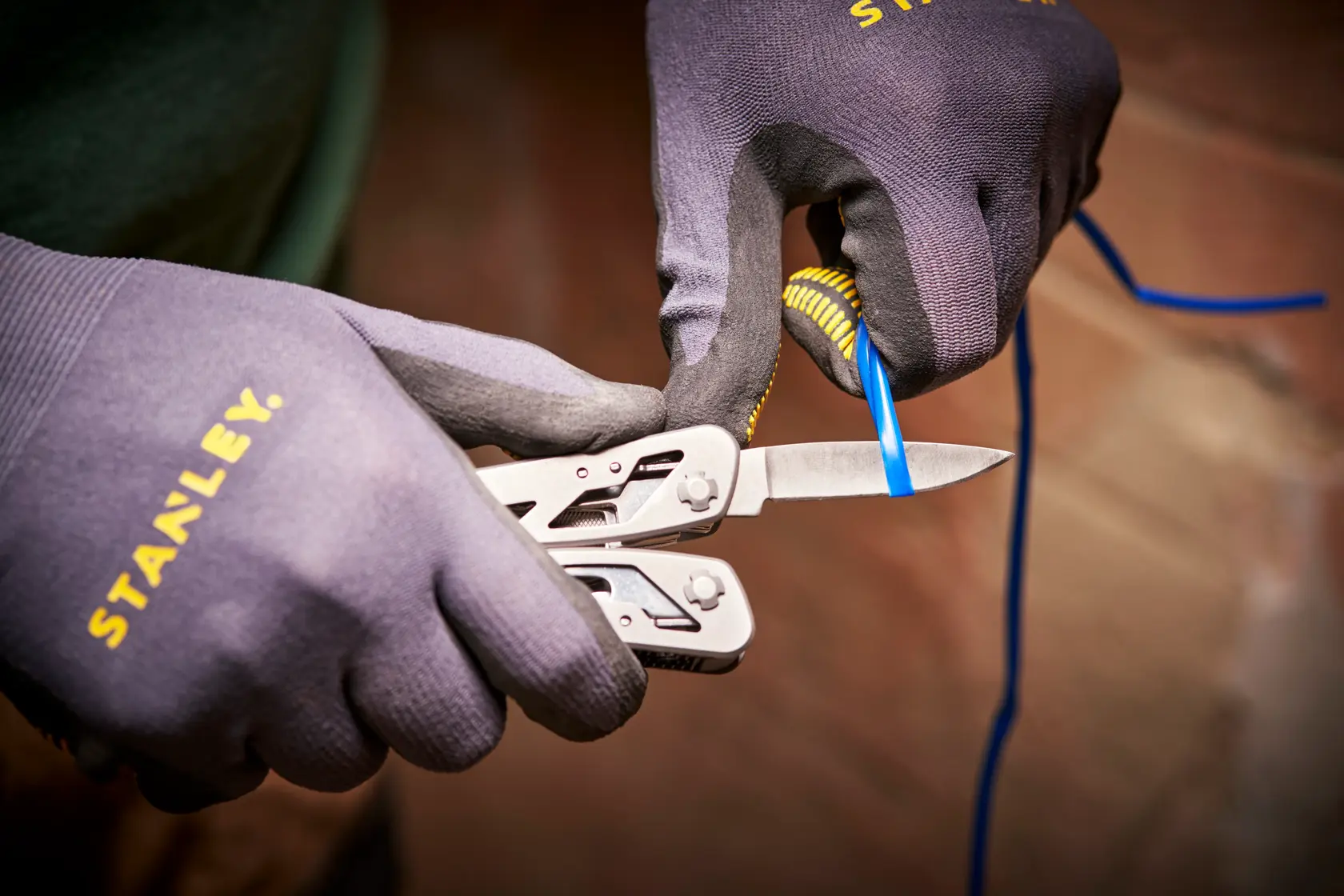 STANLEY 0-84-519 multiherramienta cortando cable azul, primer plano, usado con guantes STANLEY.