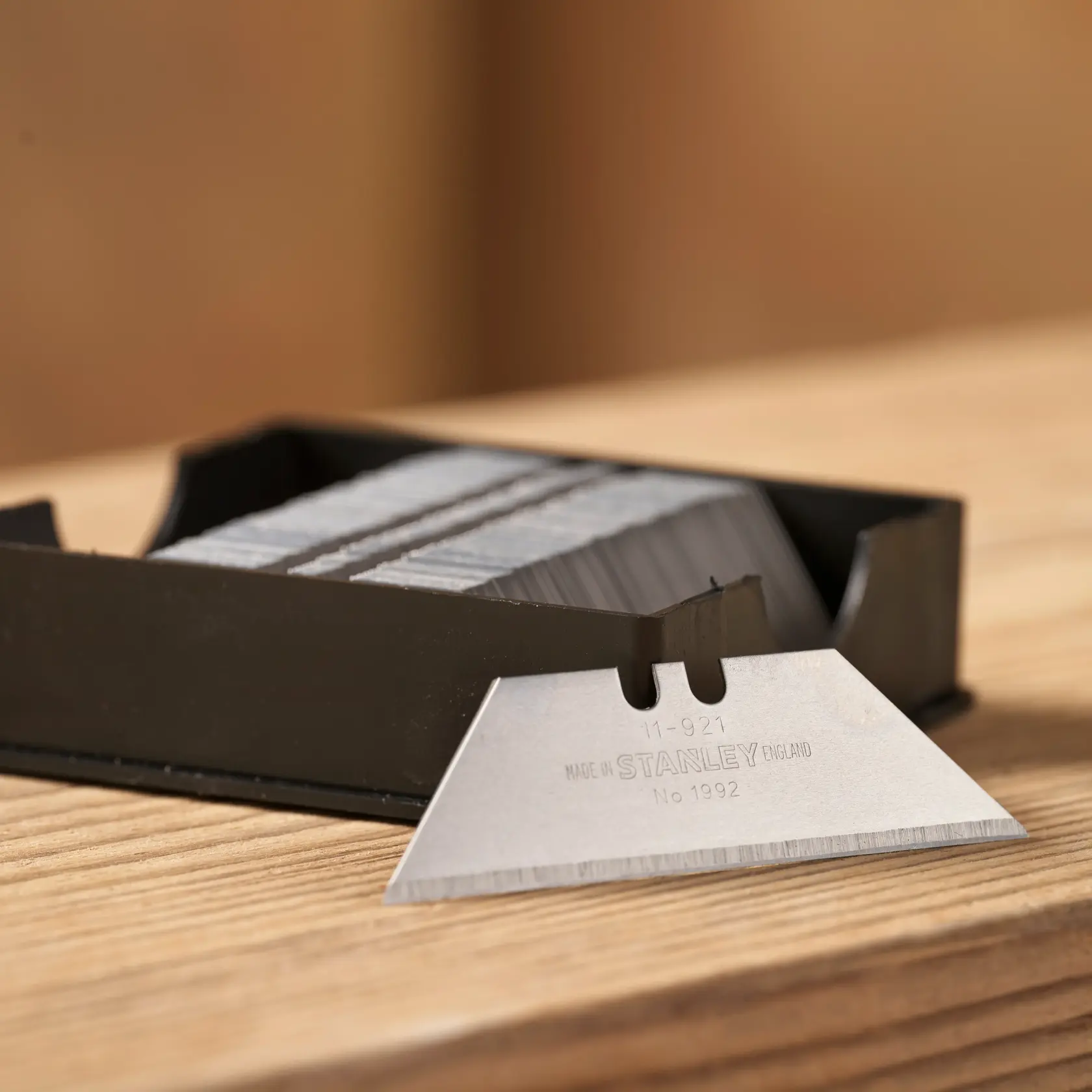 Stanley 1-11-921 cuchillas utilitarias en dispensador negro, primer plano sobre superficie de madera.