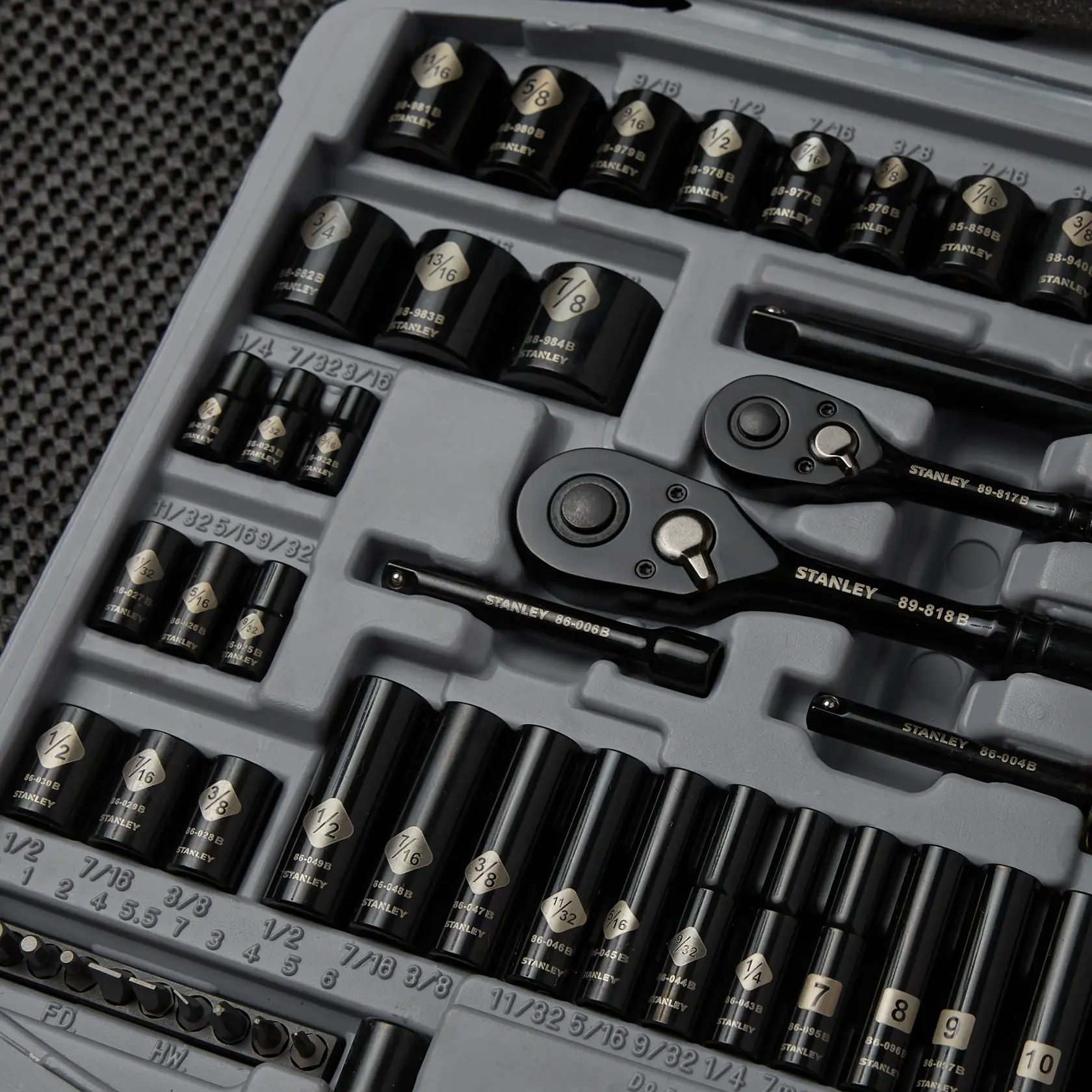 Juego de dados STANLEY 92-839 con dados, carracas y extensiones negras organizados en bandeja de espuma gris, vista superior.