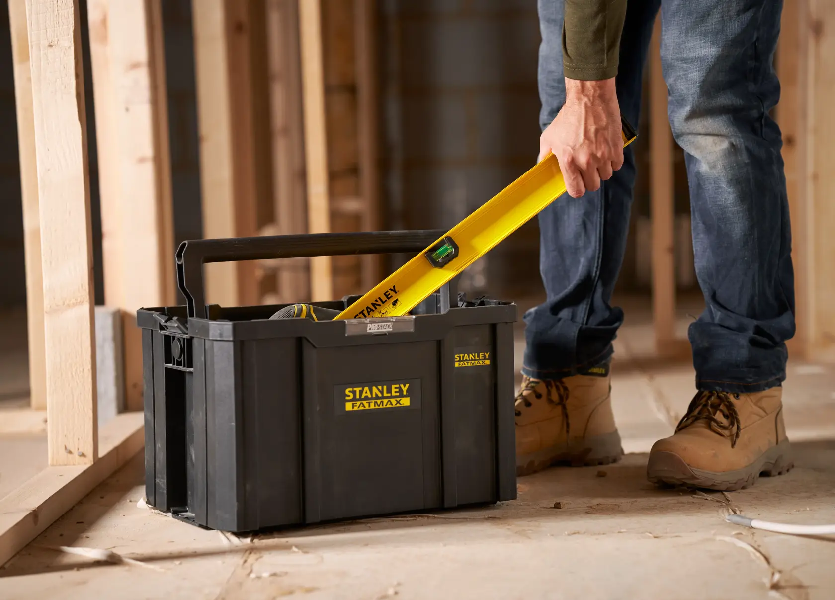 Stanley FMST1-75794 caja de herramientas con asa en obra, persona coloca nivel amarillo dentro