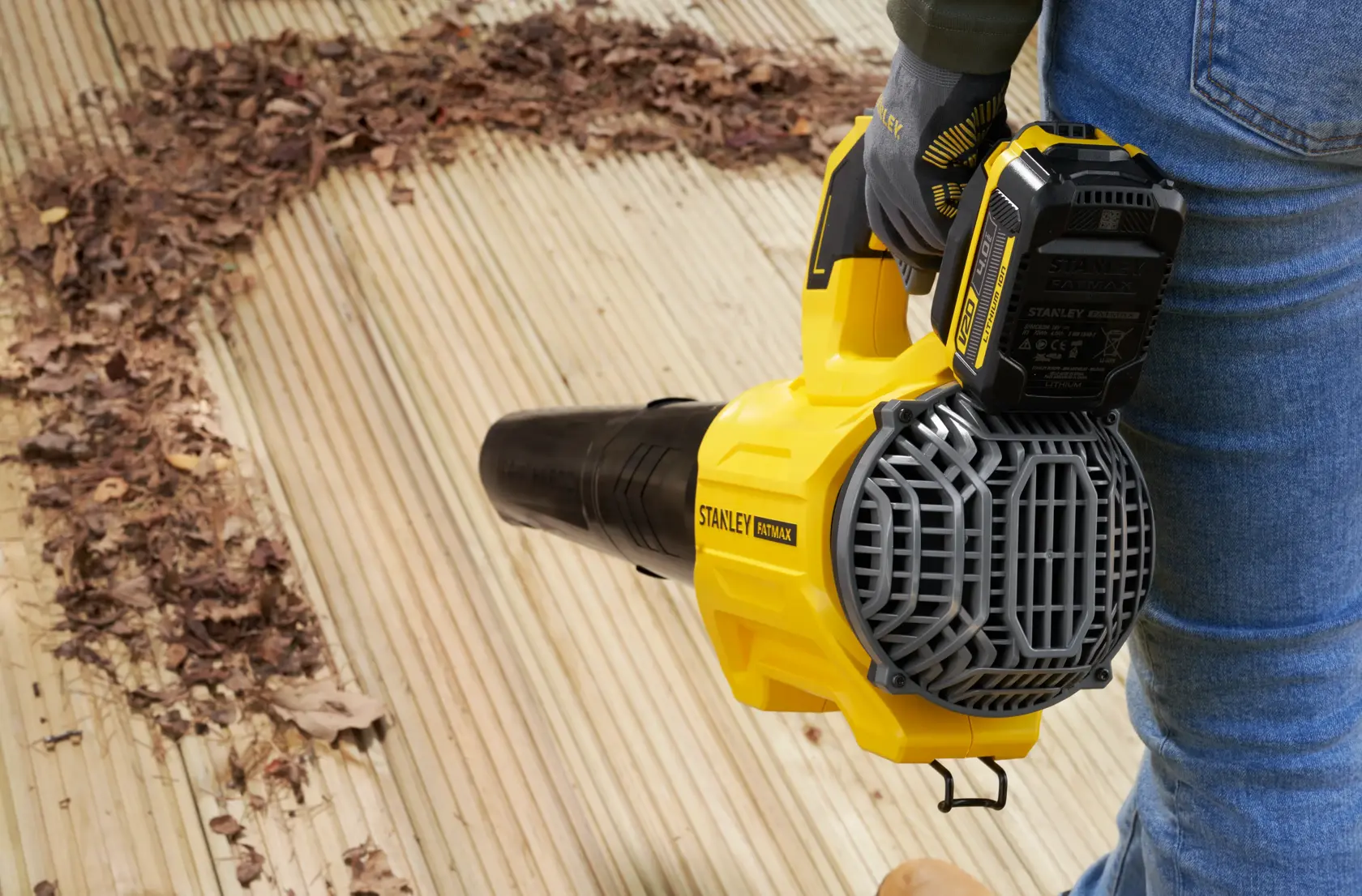 STANLEY SFMCBL730B soplador de hojas en uso sobre terraza de madera, elimina hojas secas, vista lateral.