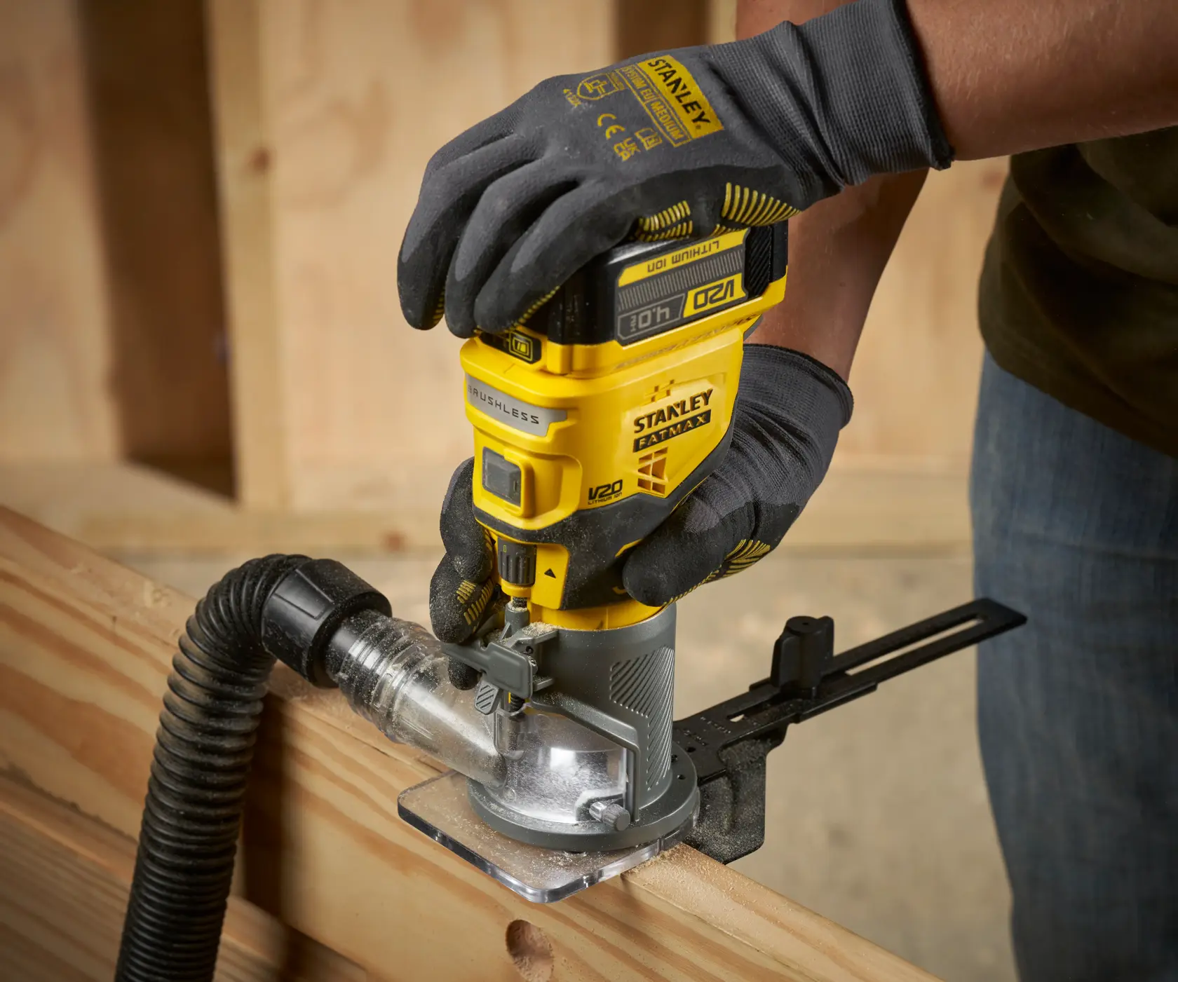 Foto del router inalámbrico para madera STANLEY SFMCW400B en uso sobre madera, detalle de herramienta amarilla y extracción de polvo.