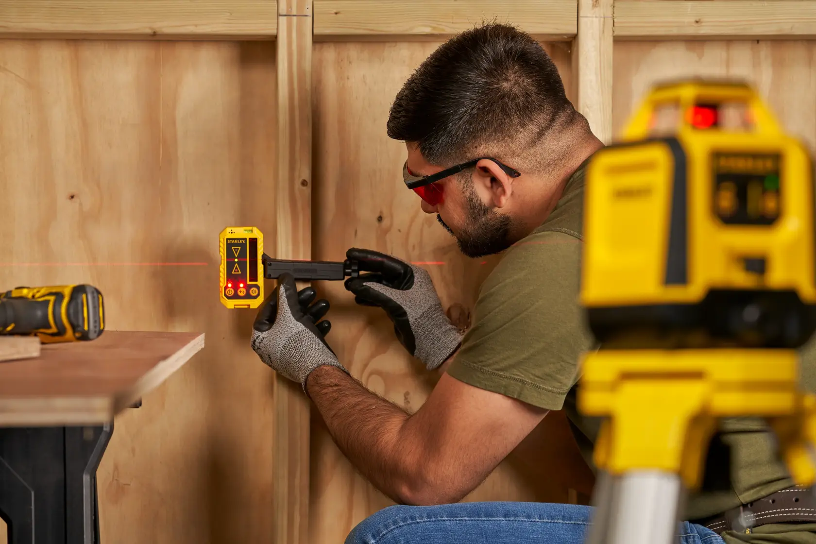 STANLEY STHT77616-0 detector láser en uso para nivelar paredes, con guantes y equipo de nivel láser.