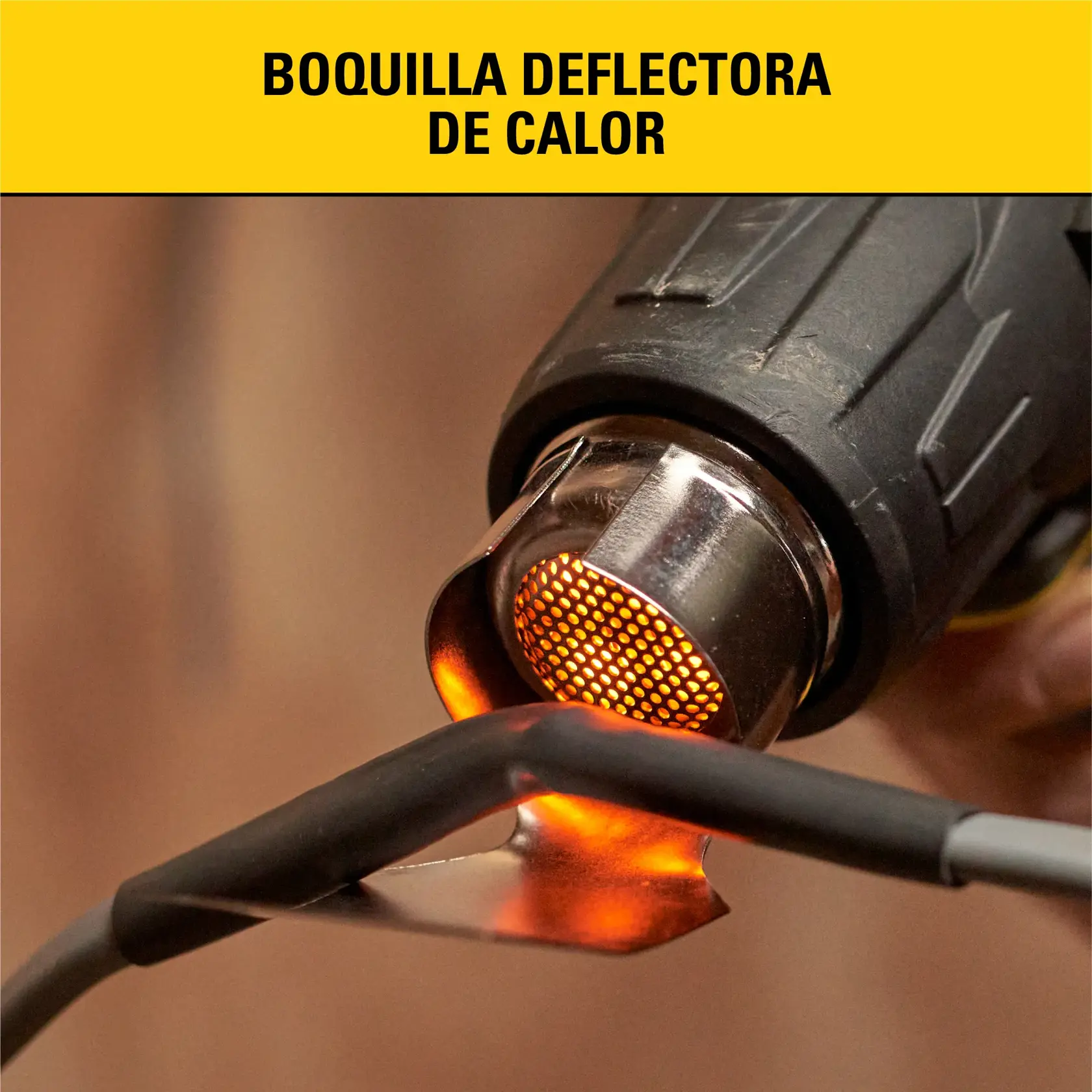 Primer plano de una pistola de calor negra con una boquilla deflectora de calor metálica. La boquilla brilla en color naranja, dirigiendo el calor hacia un cable en uso.