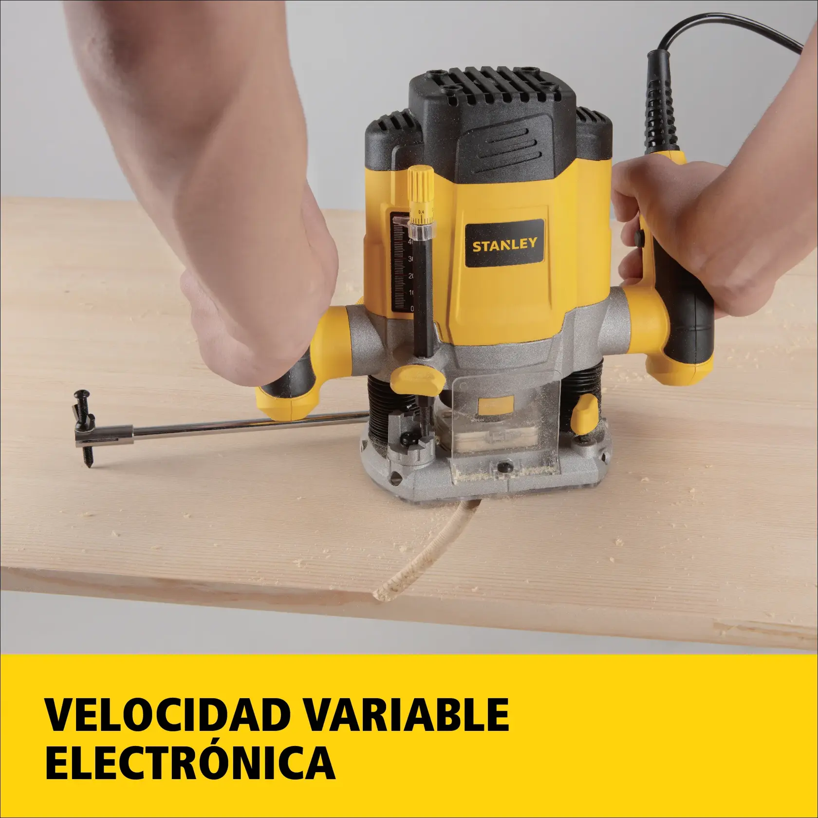 Persona utilizando una fresadora STANLEY SRR1200 con velocidad electrónica variable sobre una superficie de madera. La herramienta es amarilla y negra, y el texto en la parte inferior dice 'Velocidad variable electrónica'.