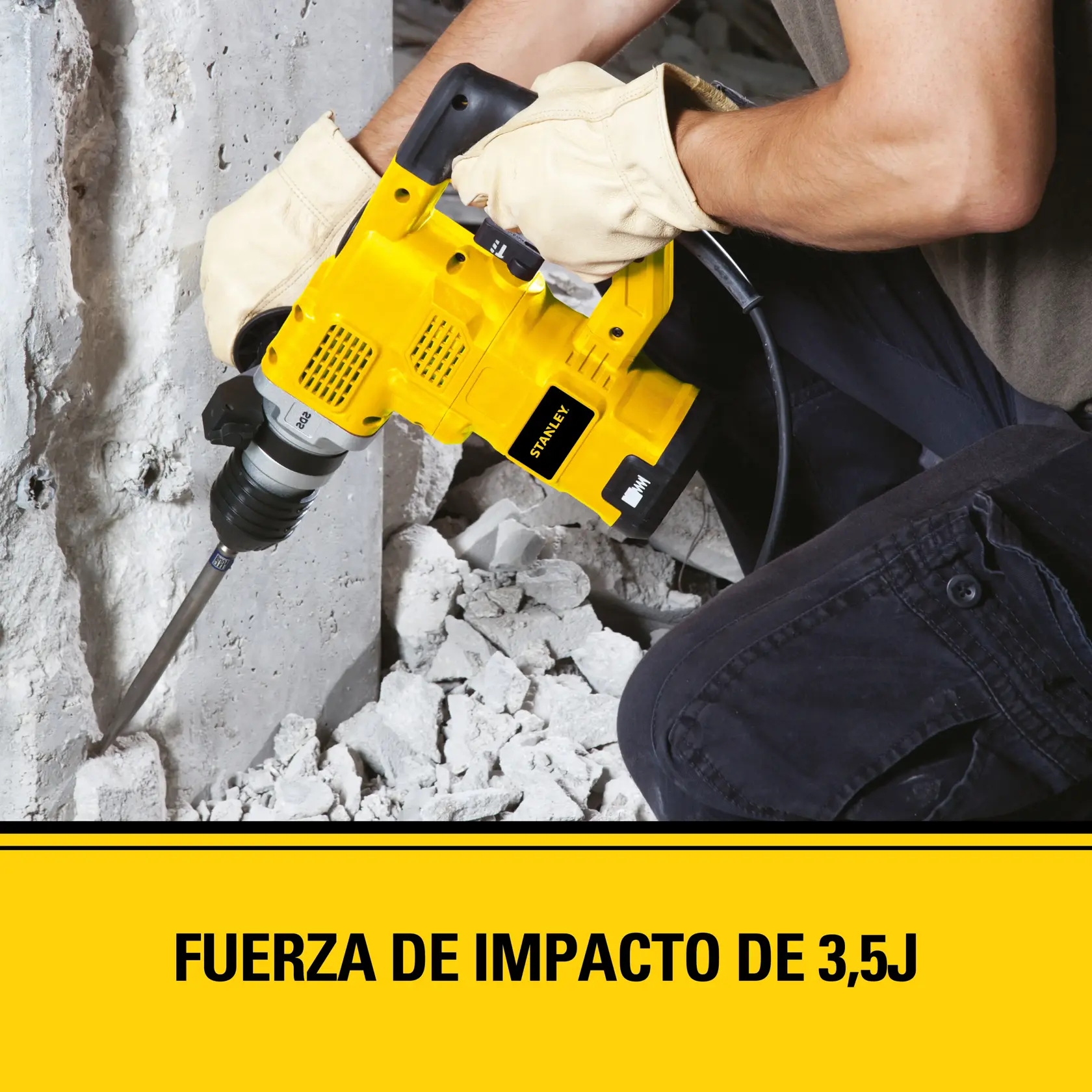 Persona con guantes usando un martillo perforador amarillo Stanley para romper concreto. Se observa escombros en el suelo. El texto en la imagen dice: 'Fuerza de impacto de 3,5J.'