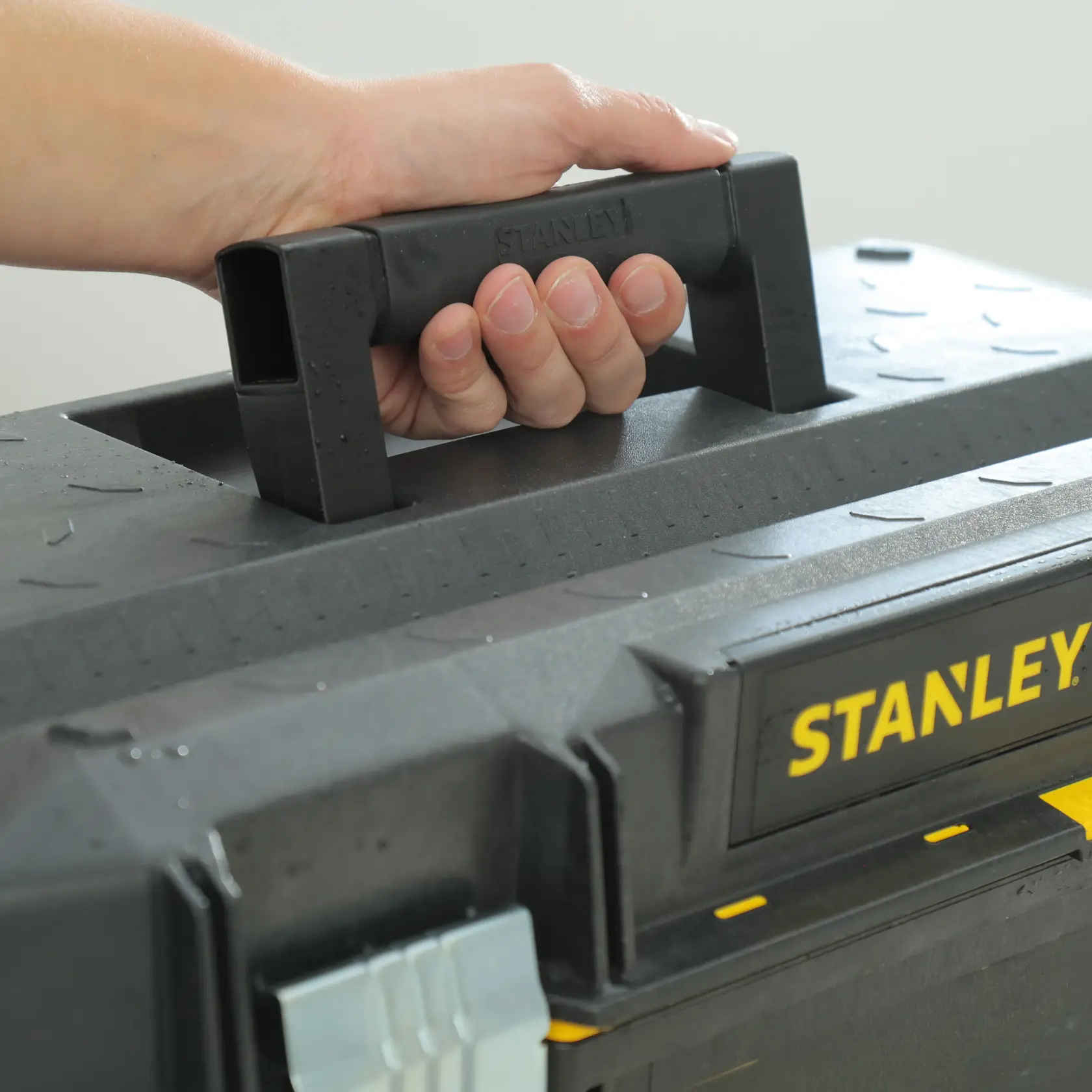 STANLEY 023001W FATMAX caja de herramientas en primer plano, mango negro sostenido, etiqueta amarilla visible.