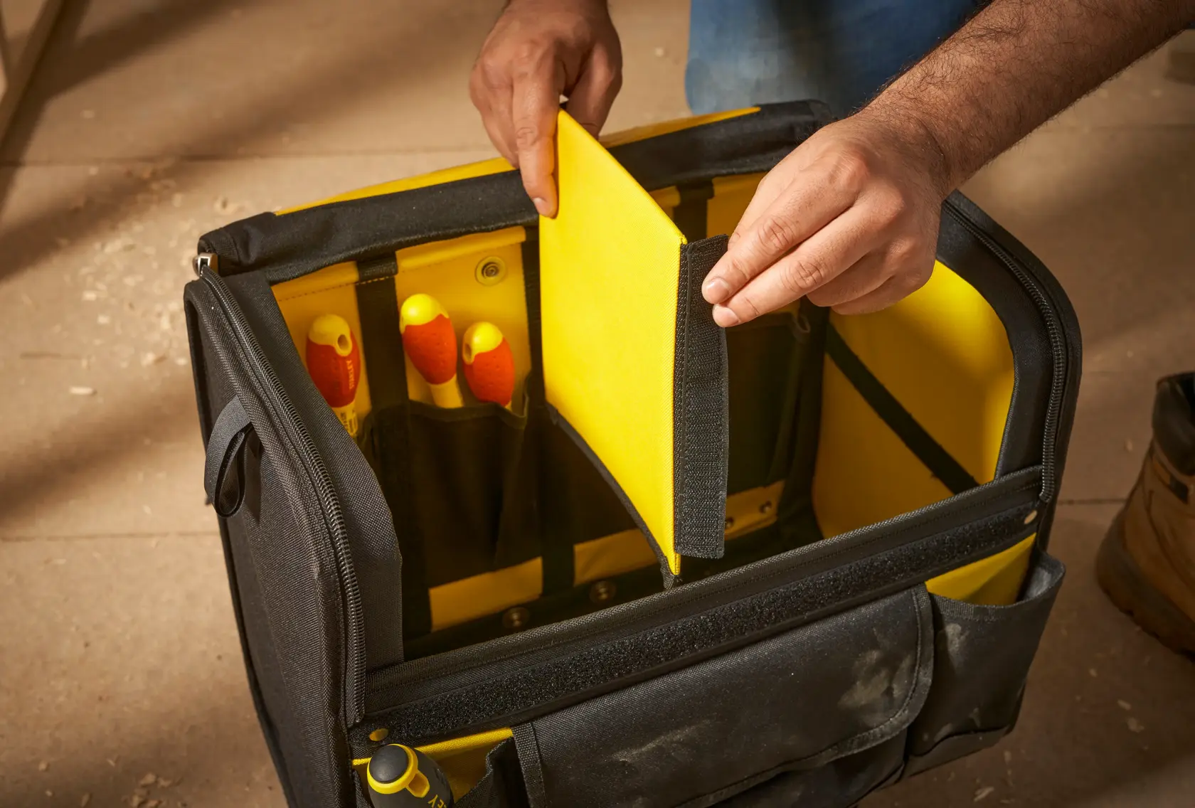 STANLEY 1-97-515 bolsa de herramientas con divisor interior amarillo, mano sosteniendo divisor, ángulo frontal.