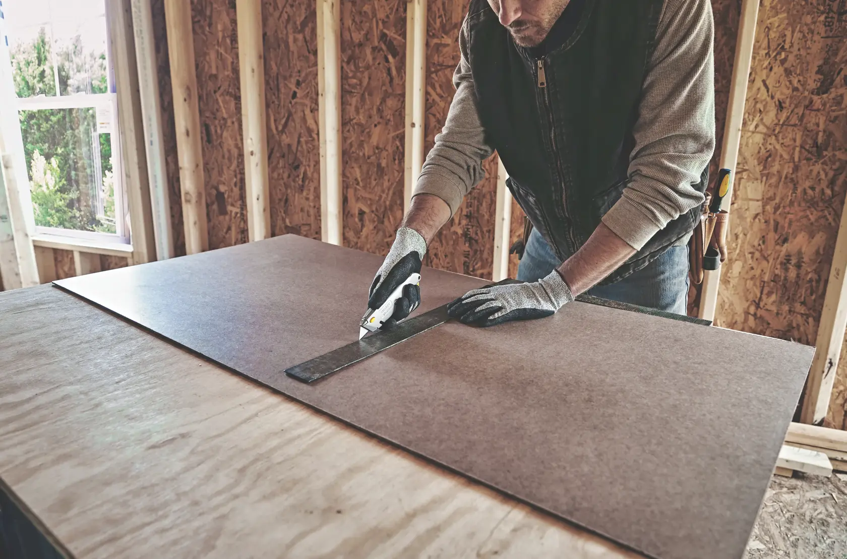 STANLEY 10-499 cuchillo utilitario cortando material de tablero con una regla metálica en obra en construcción.