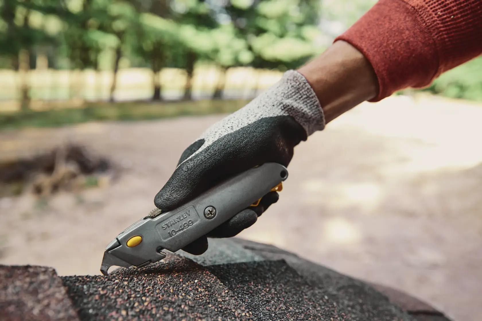 Stanley 10-499 cuchillo utilitario usado en material de tejado al aire libre, ángulo lateral cercano.