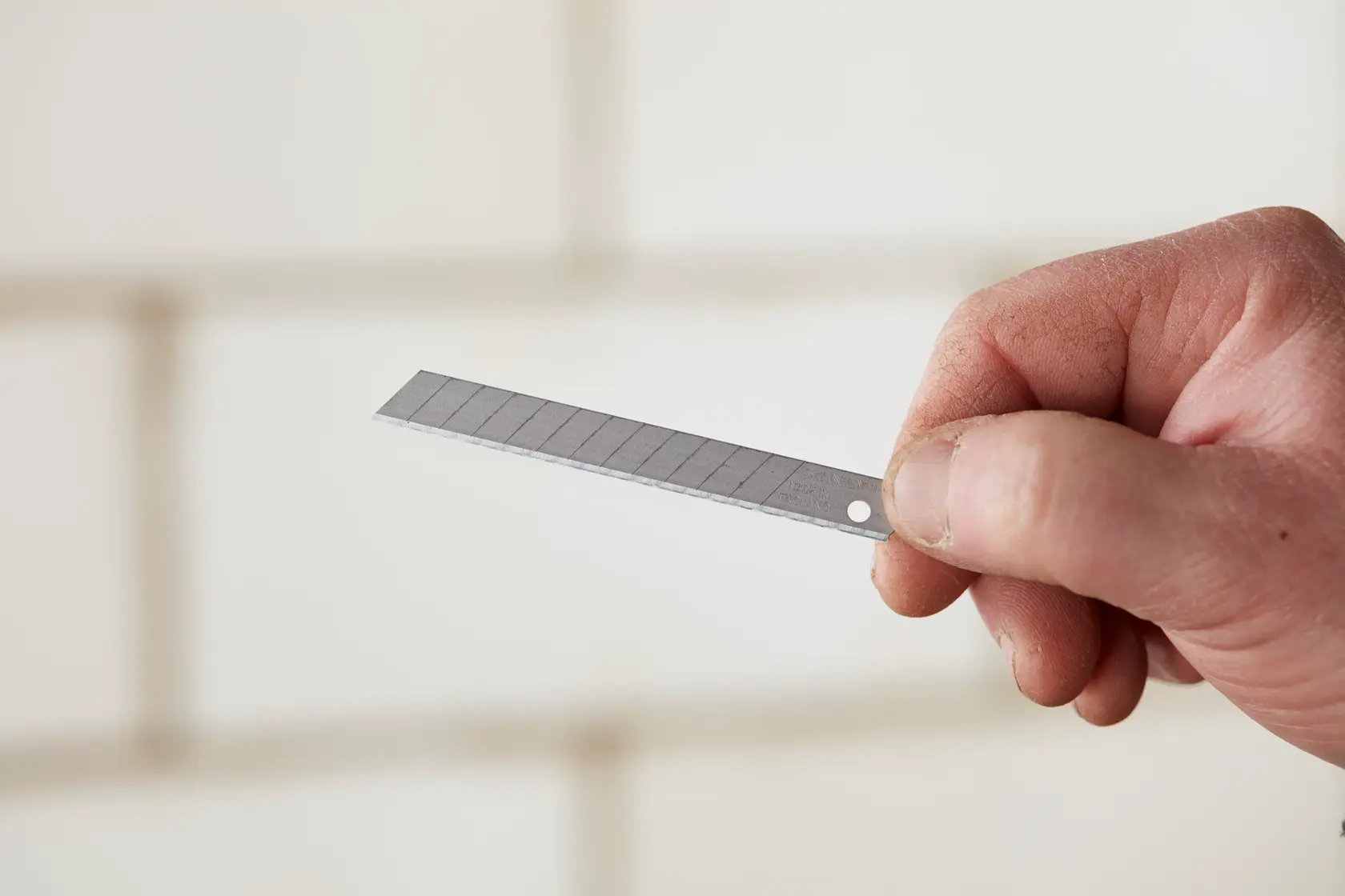 Fotografía de hoja de cuchilla para cutter STANLEY 11-300 sostenida en la mano, mostrando la hoja segmentada de metal.
