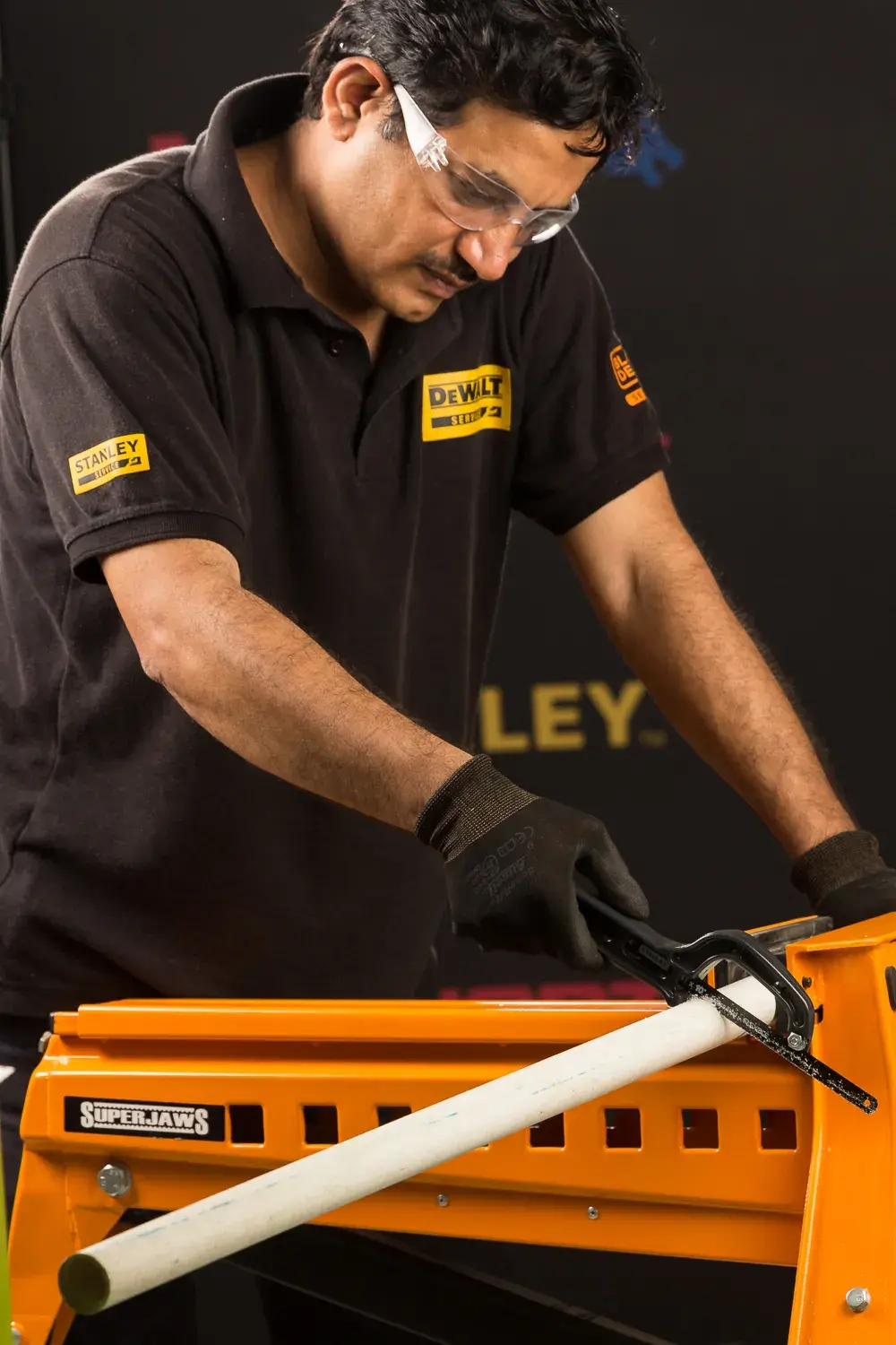 STANLEY 20-807 sierra manual cortando tubo sobre banco de trabajo naranja, ángulo de primer plano.