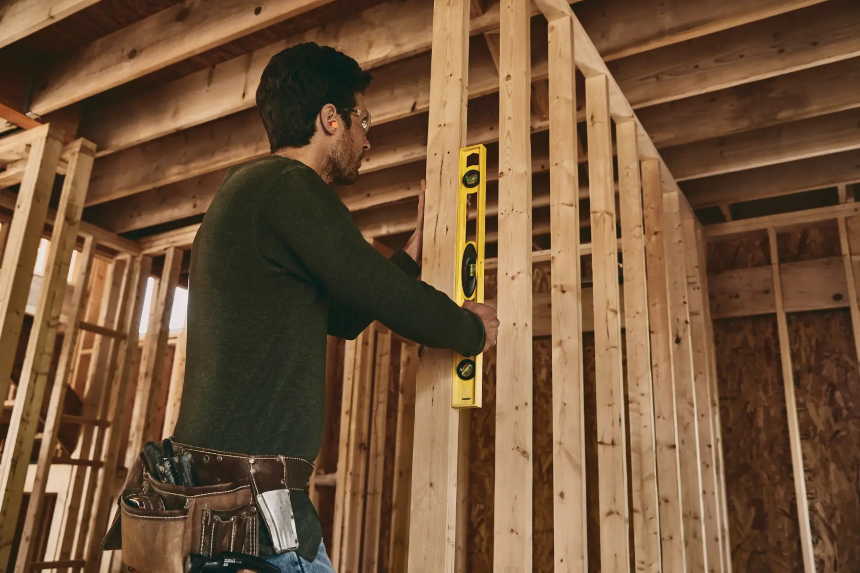 Herramienta de nivel STANLEY 42-468 usada por trabajador en estructura de madera sin terminar, foto lateral.