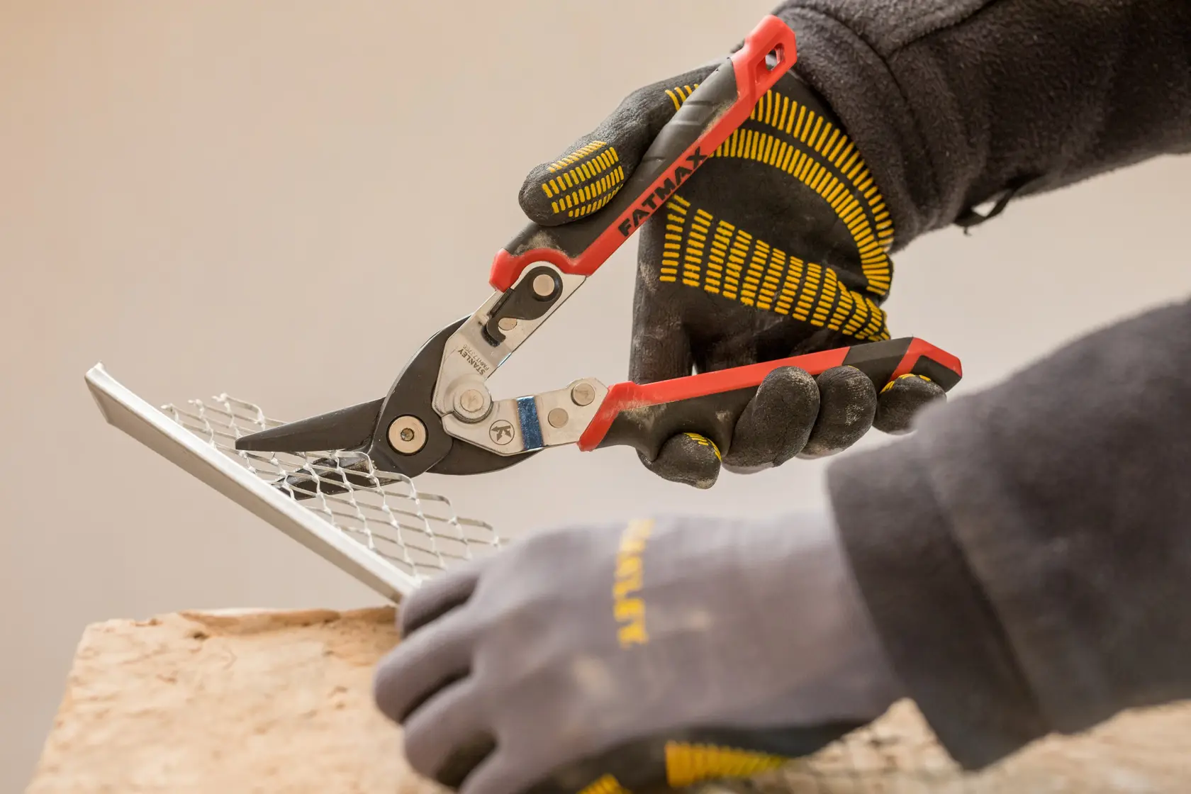 STANLEY FMHT73755 tijeras para metal cortando malla, foto de primer plano, guantes negros y amarillos.
