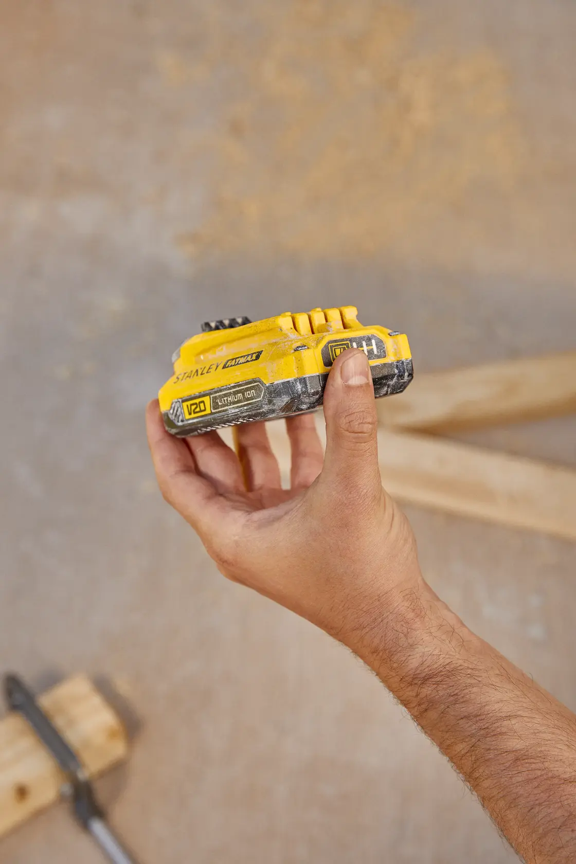 Foto de la batería de litio STANLEY V20 SB201-B2 sostenida en la mano, fondo de construcción, categoría fotografía.
