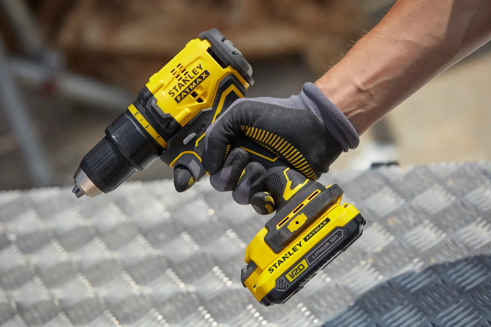 Taladro inalámbrico amarillo Stanley SBD710C2K-BR en uso, vista cercana, trabajador con guante negro.