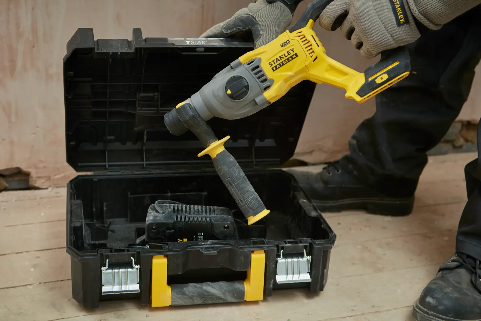 STANLEY SBH900M2K-B3 martillo rotatorio sostenido sobre caja negra y amarilla abierta en una obra.