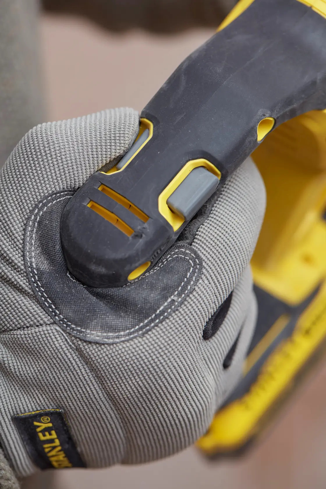 Fotografía de una mano enguantada sujetando el mango de una herramienta eléctrica STANLEY SBH900, con detalles en negro y amarillo.
