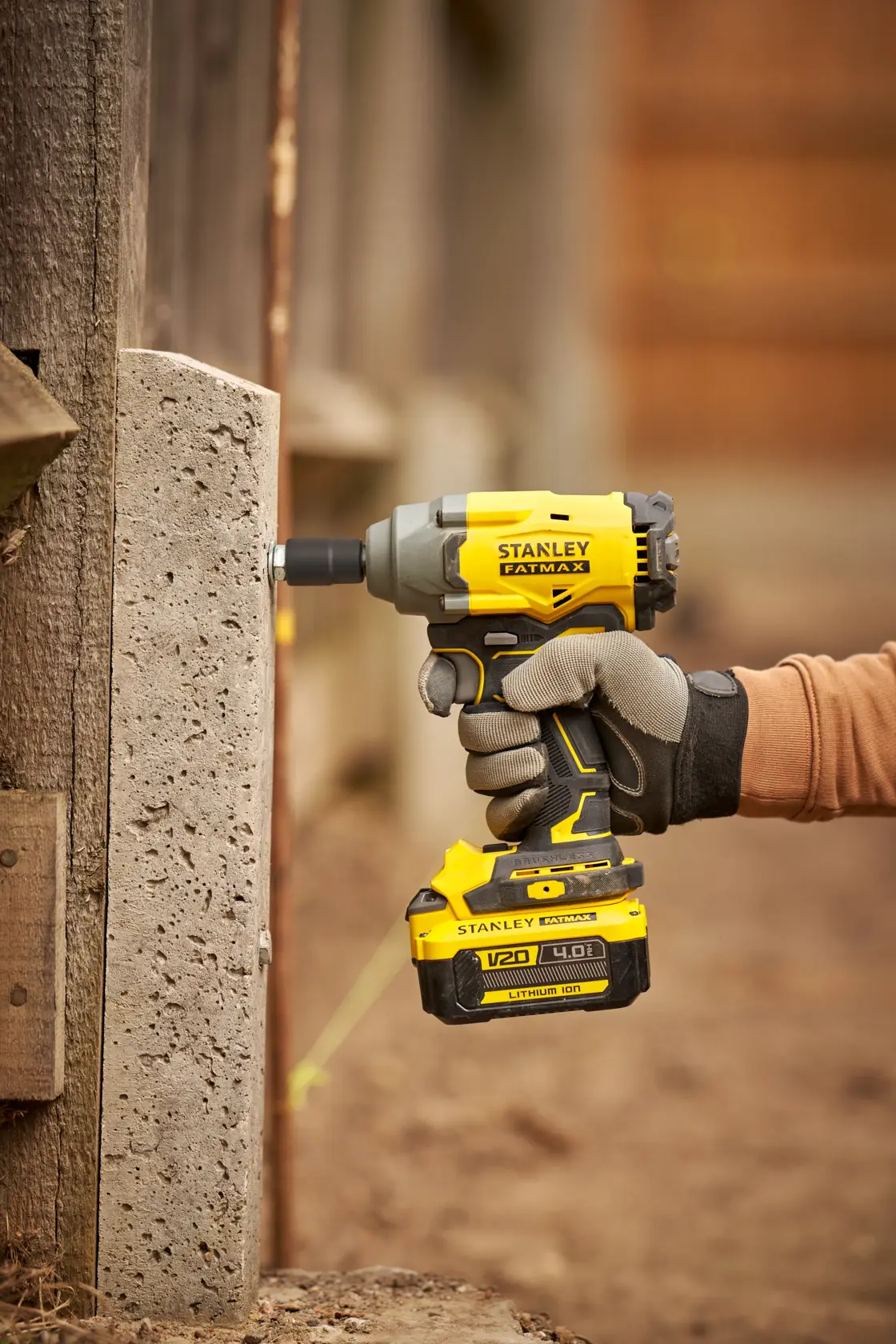 Stanley SBW920 atornillador de impacto sostenido contra concreto, herramienta inalámbrica FATMAX amarilla y negra al aire libre.