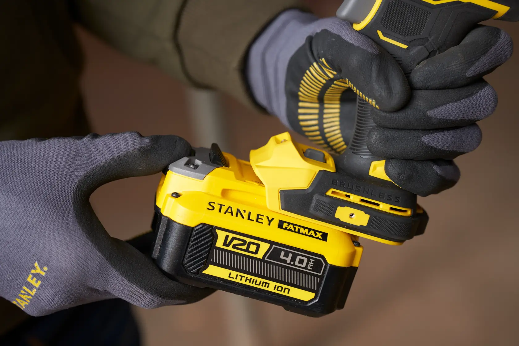 Fotografía de la herramienta eléctrica STANLEY SBW940 con batería V20 4.0Ah de ion-litio amarilla y negra siendo colocada por manos enguantadas.