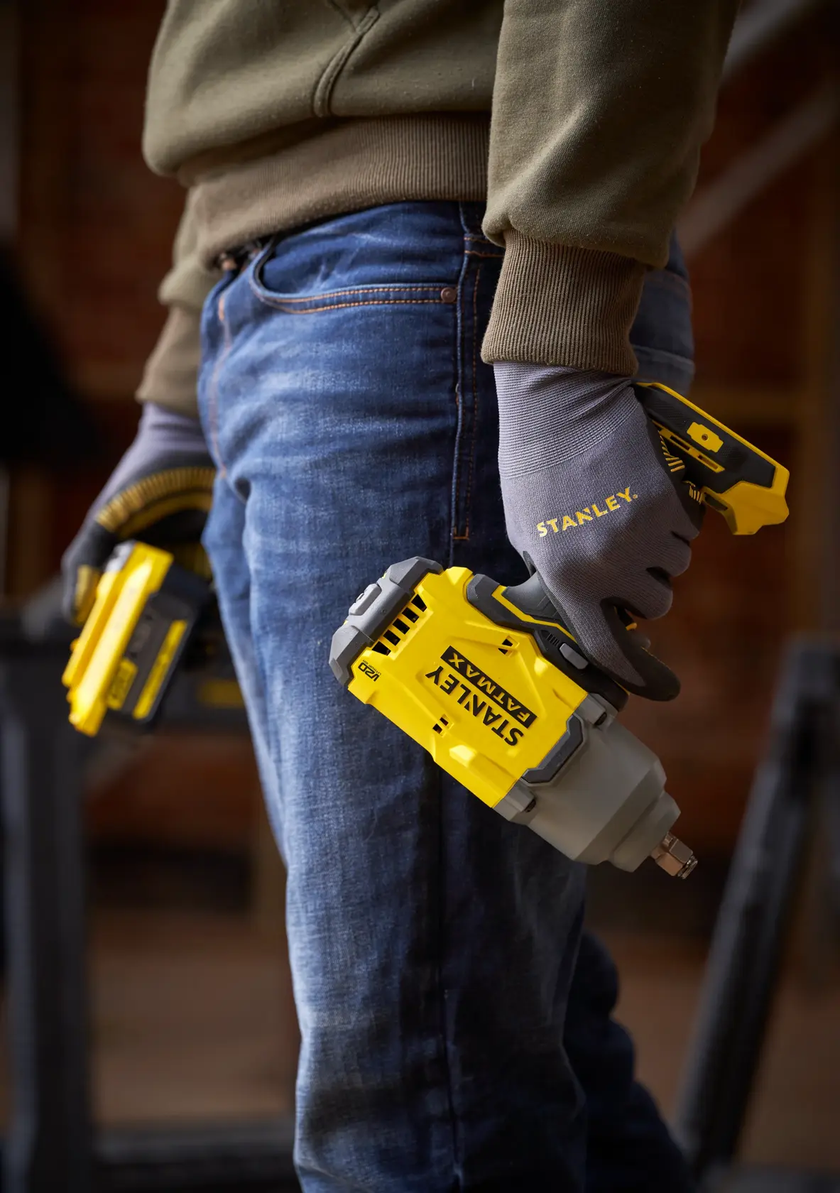 Llave de impacto inalámbrica STANLEY SBW940 sostenida por trabajador con guantes STANLEY, vista lateral.
