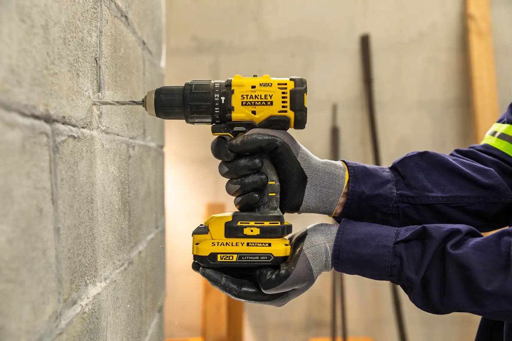 Taladro inalámbrico STANLEY SCD712 perforando una pared de concreto, trabajador con guantes.