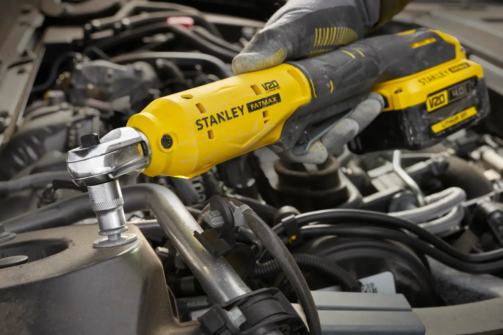 Herramienta de carraca inalámbrica STANLEY SCF930 usada en perno de motor, primer plano, diseño amarillo y negro.