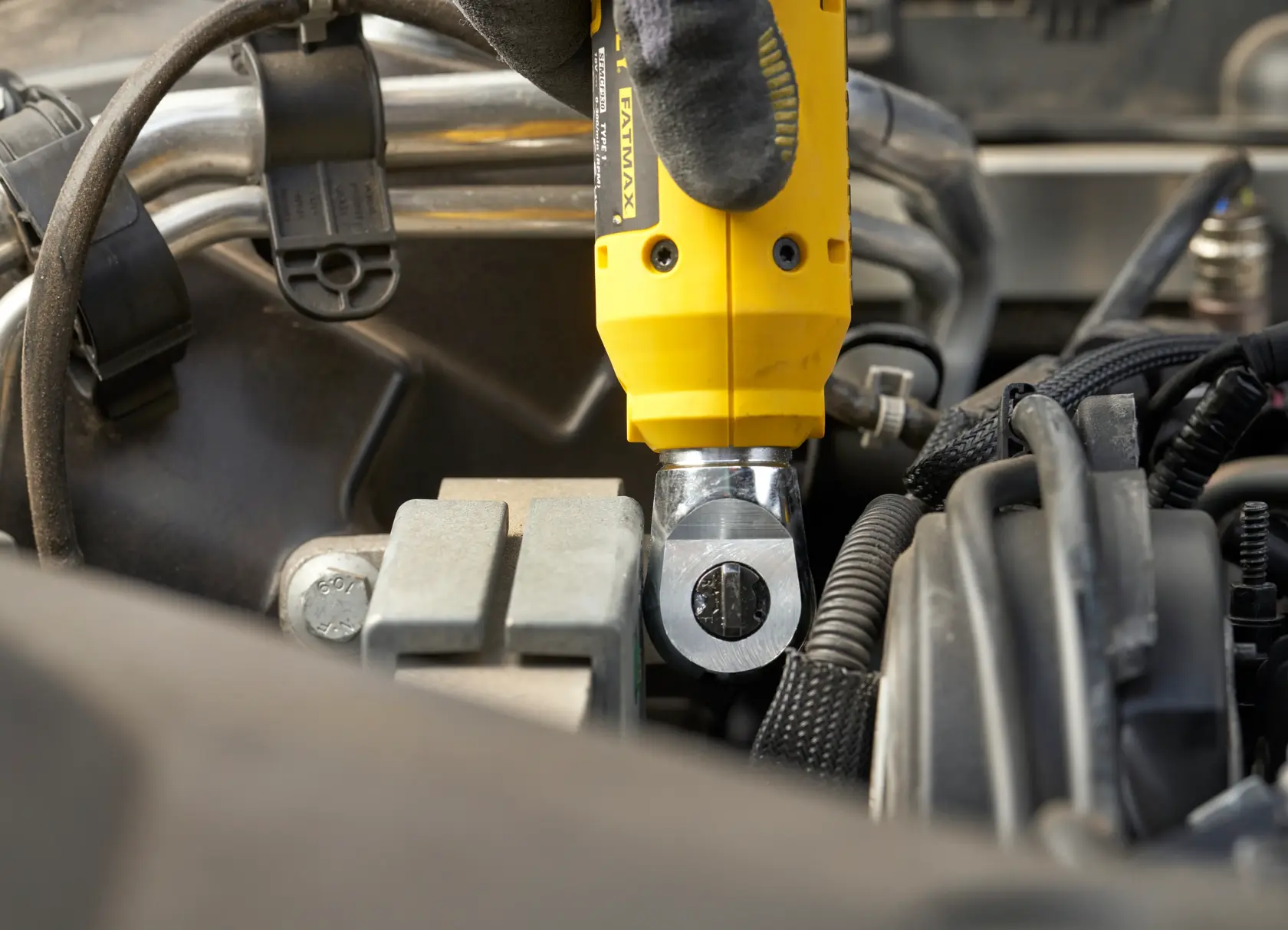 Herramienta manual STANLEY SCF930 en uso, ajustando un perno en un compartimiento de motor, vista en primer plano.