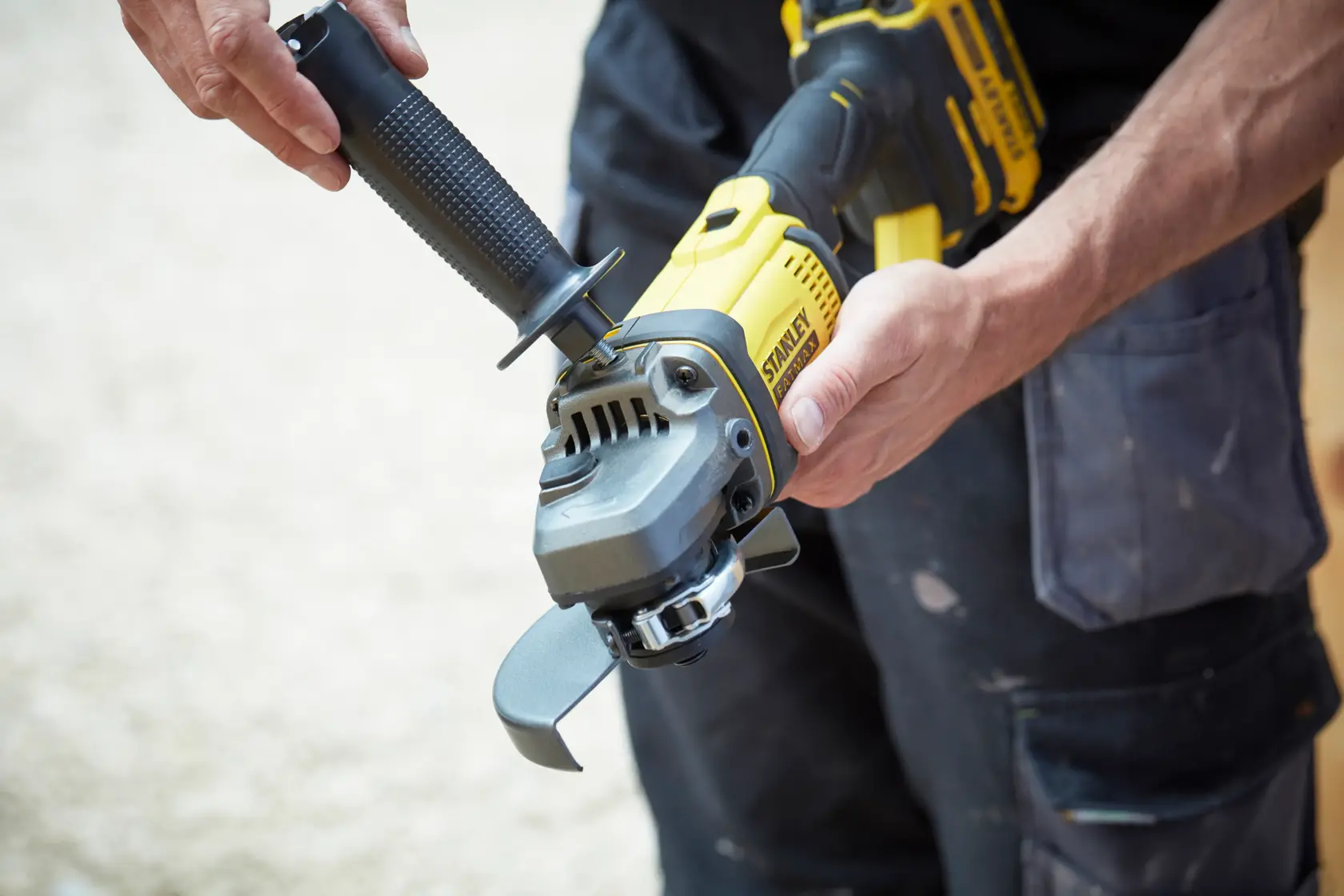 STANLEY SCG400 amoladora angular sostenida por una persona, diseño amarillo y negro, vista de cerca.