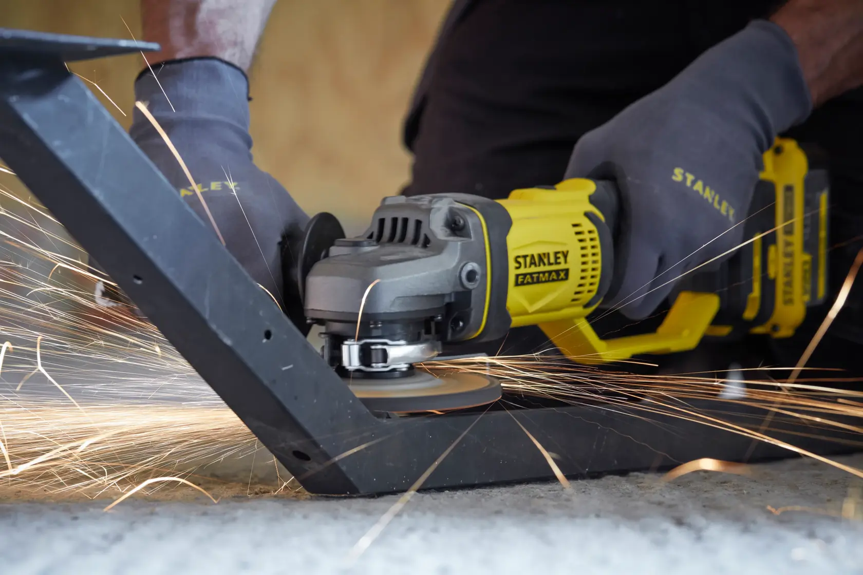 Stanley SCG400M2K-KR amoladora angular en uso, lijando metal con chispas, primer plano de herramienta y manos enguantadas.
