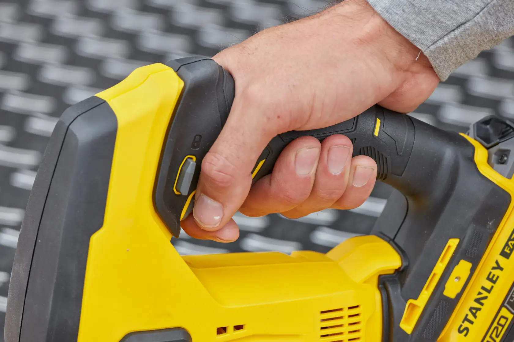 Fotografía del mango de herramienta eléctrica STANLEY SCJ600M2K amarillo y negro sostenido por una mano, vista de cerca.