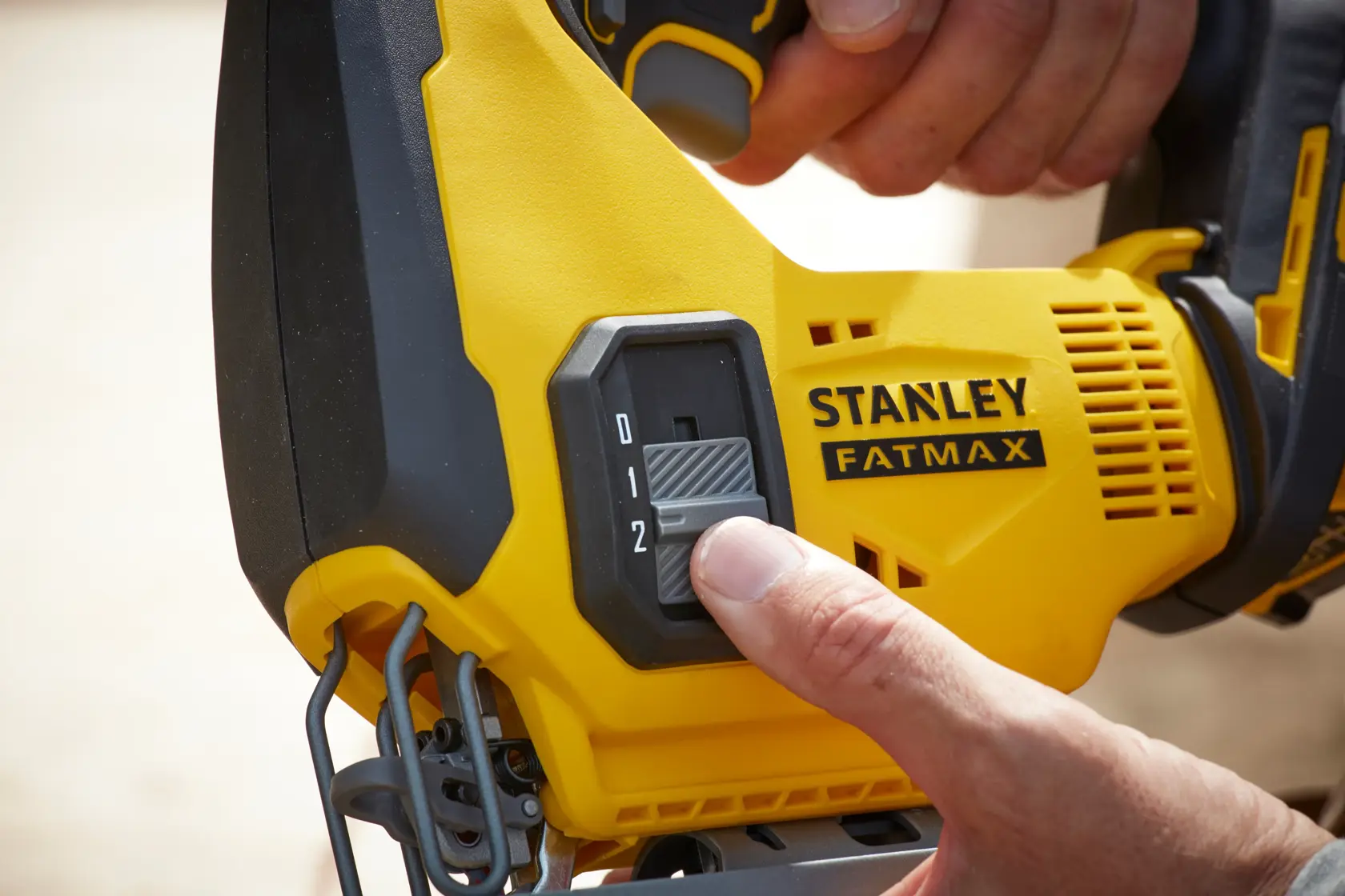 STANLEY SCJ600B control de velocidad de caladora en primer plano, carcasa amarilla y negra, mano ajustando.