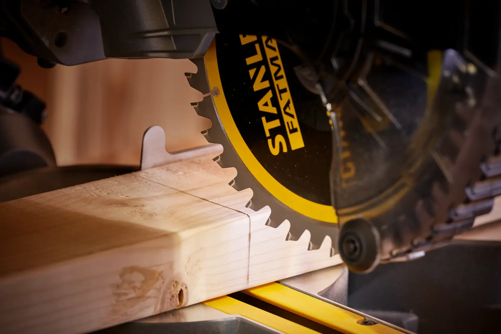 STANLEY SCM701M1 sierra ingletadora cortando tablón de madera, vista cercana mostrando hoja y madera.