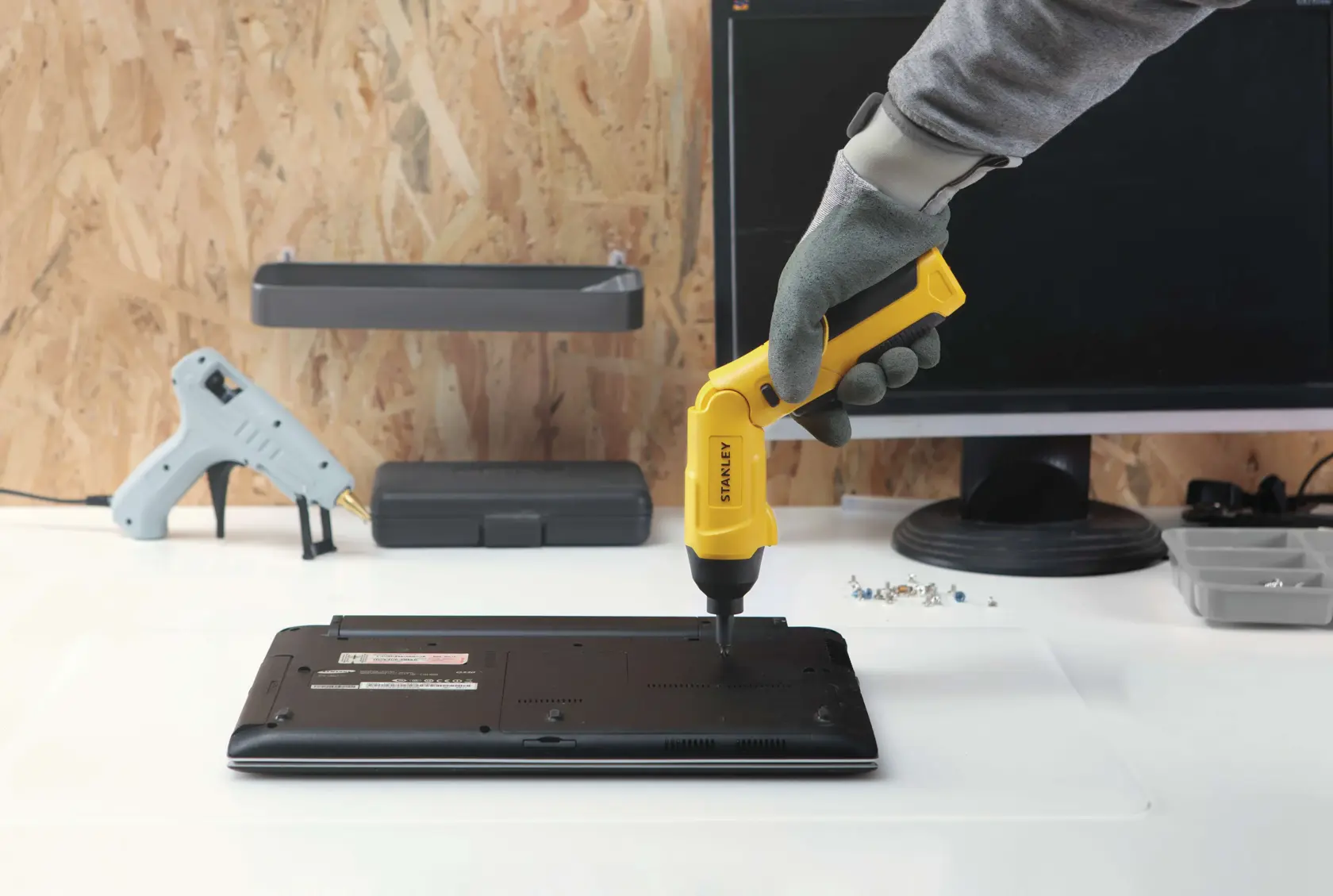 Fotografía del destornillador inalámbrico STANLEY SCS4K usado para reparar una laptop en un escritorio, en taller.
