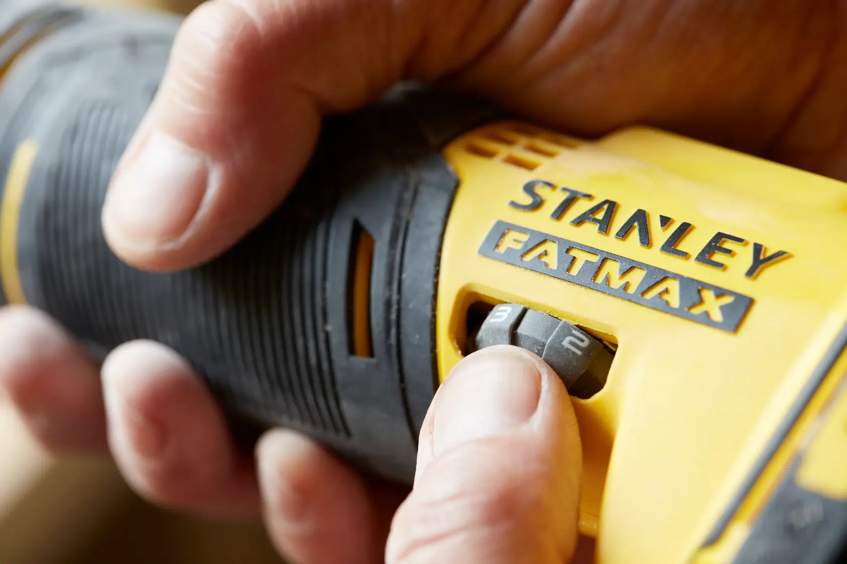 STANLEY SCT500 herramienta eléctrica en primer plano, mano ajustando dial amarillo y negro, etiqueta FATMAX visible.