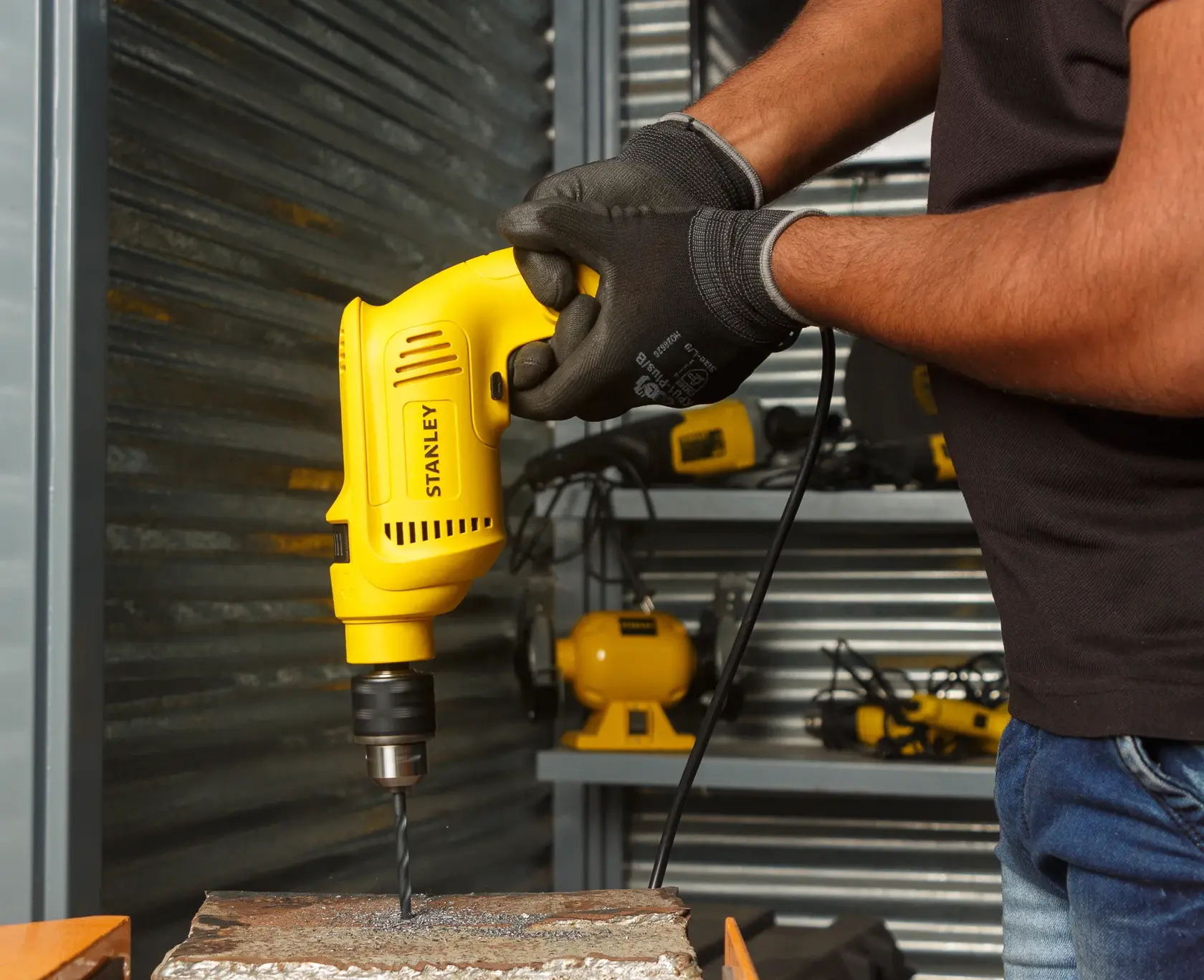 STANLEY SDH600KP taladro amarillo con cable usado en pared de concreto, primer plano en taller.