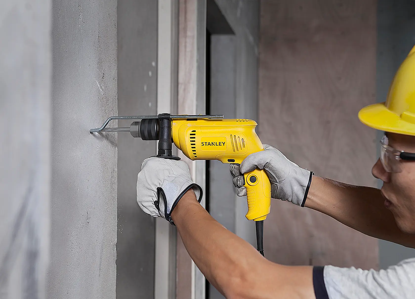 Taladro amarillo Stanley SDH600 en uso sobre pared de concreto, ángulo lateral, escena de construcción.