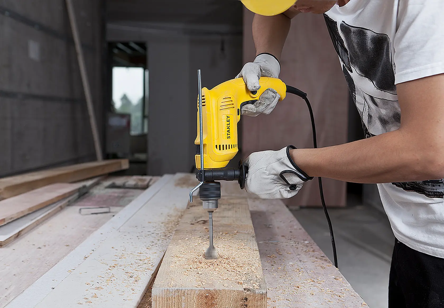 Fotografía de un trabajador usando un taladro con cable STANLEY SDH600 para perforar una tabla de madera en el taller.