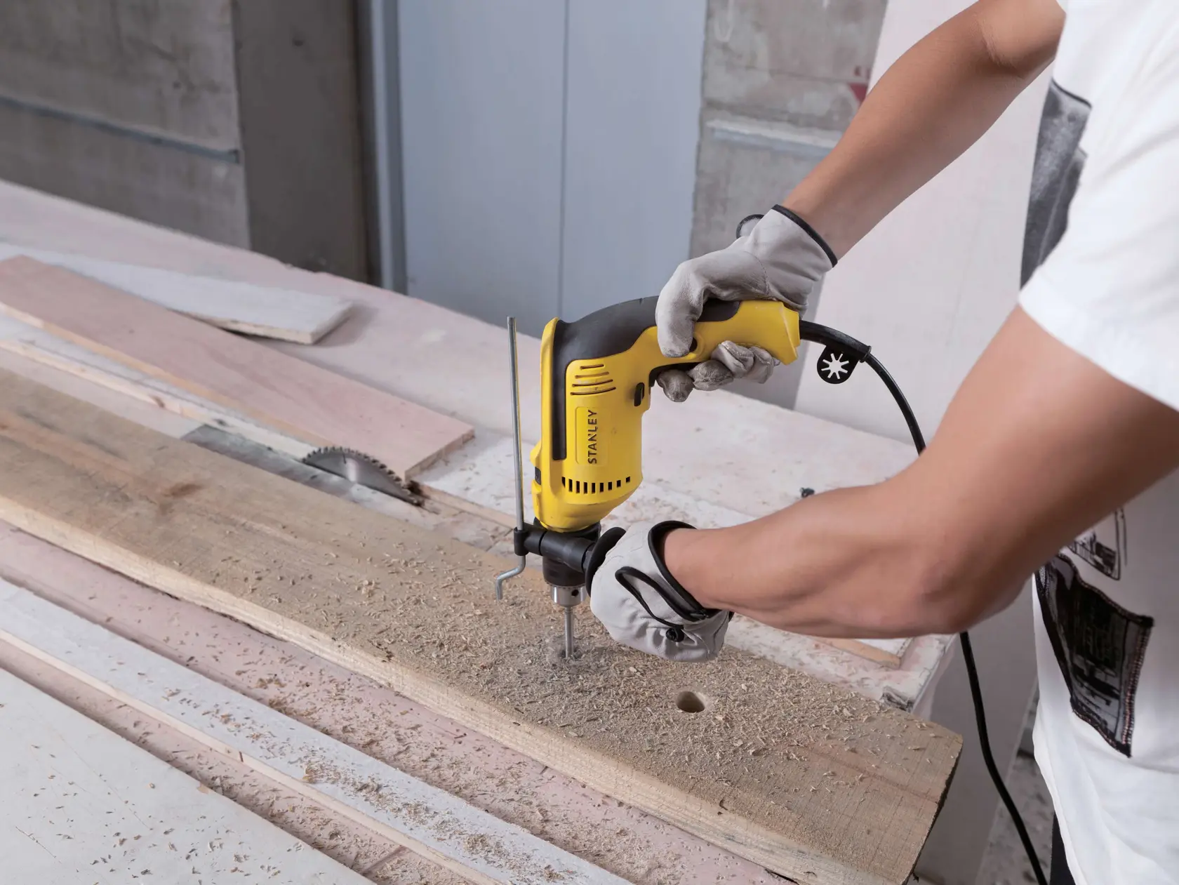 Fotografía de una persona usando un taladro eléctrico STANLEY SDH700 en madera en un taller.