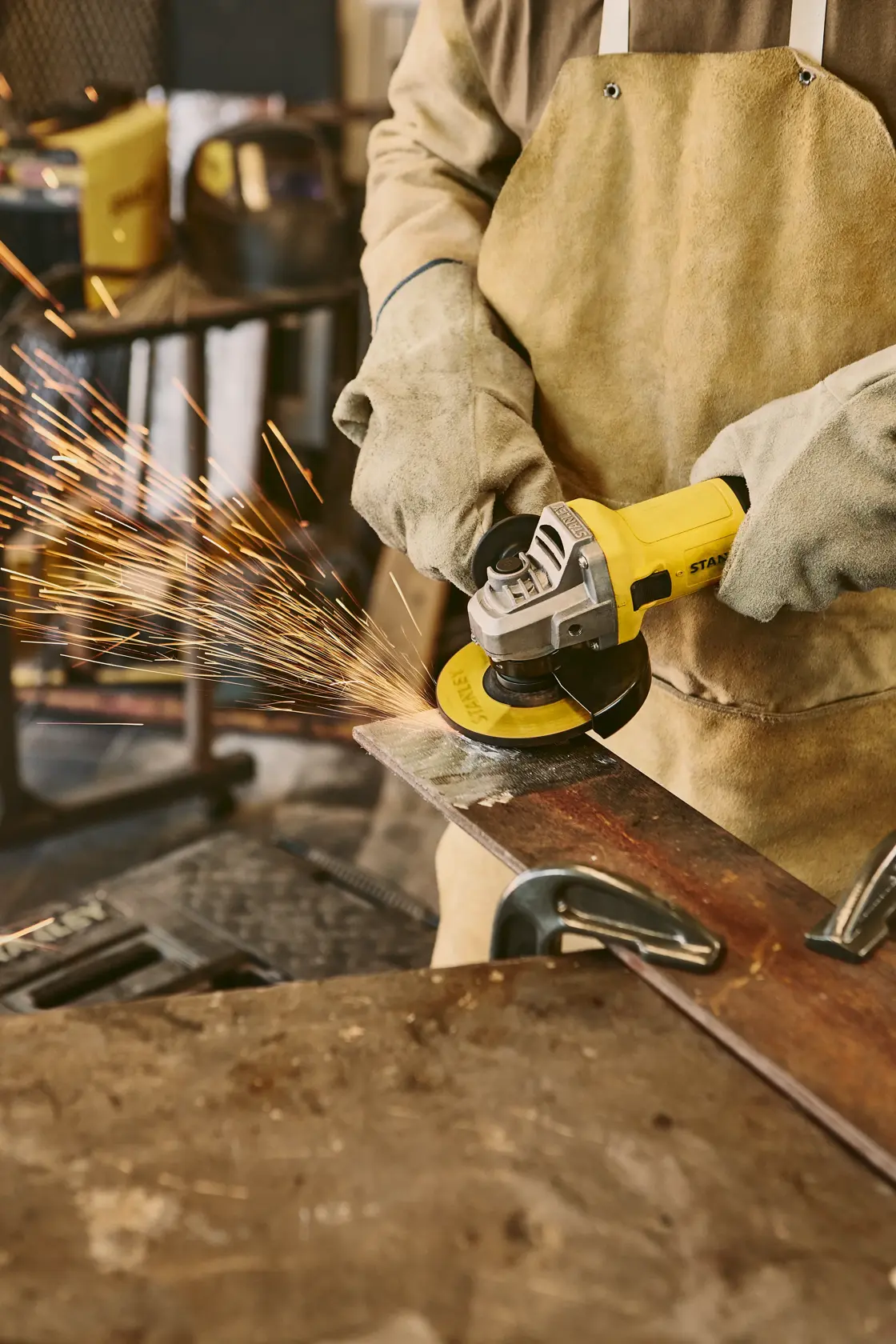 STANLEY SG7115-B3 esmeril angular en uso, cortando metal con chispas, fotografía de taller en primer plano.
