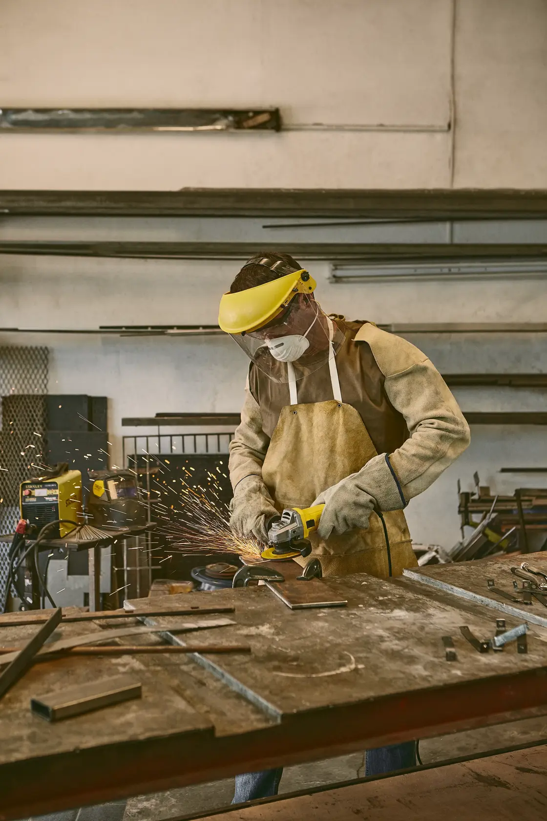 STANLEY SG7115-B3 amoladora en taller, trabajador con equipo de seguridad usando la herramienta en metal.