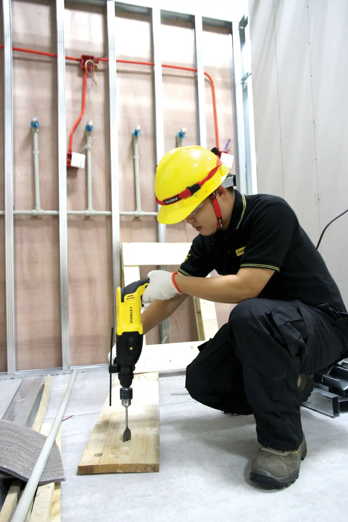 Taladro rotomartillo STANLEY SHR263K-BR en uso sobre madera, operario con casco amarillo y uniforme negro.