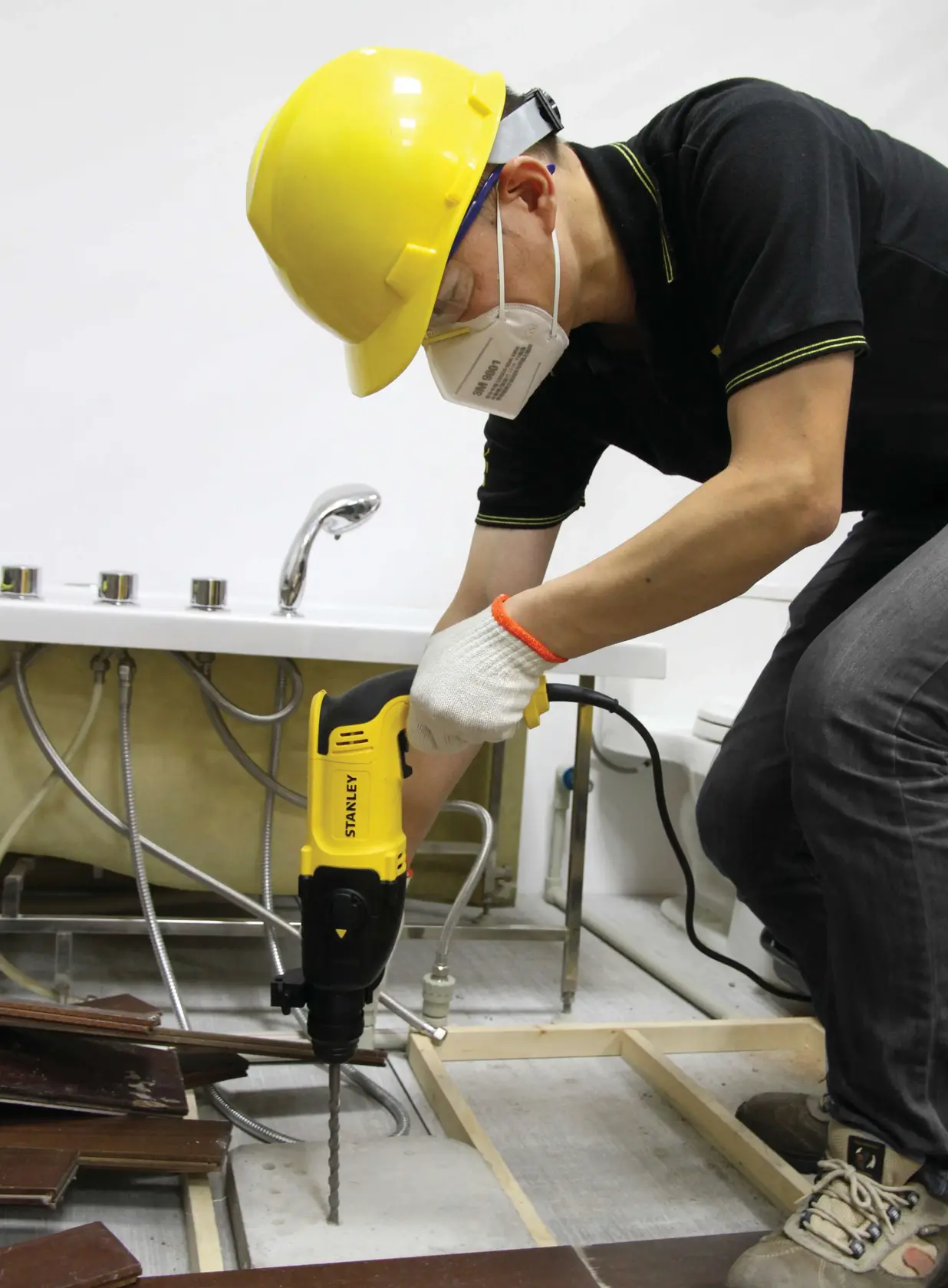 Martillo rotativo STANLEY SHR263K-BR usado para taladrar el suelo cerca de un lavabo en obra.
