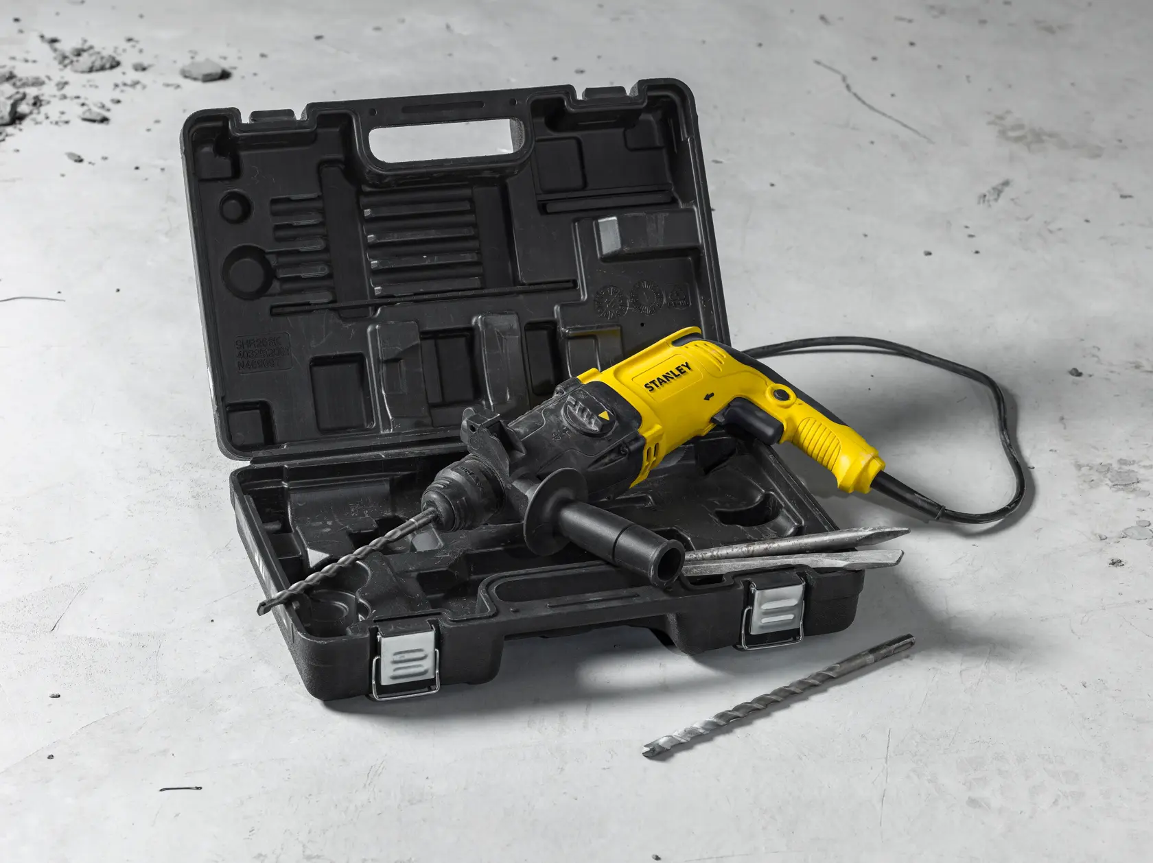 Martillo rotativo STANLEY SHR263K-BR amarillo y negro, con maletín y accesorios sobre superficie de concreto.