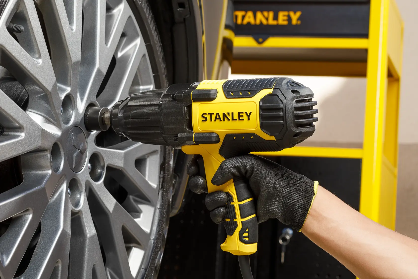 Llave de impacto Stanley SIW901-B2 utilizada en una rueda de auto, primer plano de la herramienta y llanta.