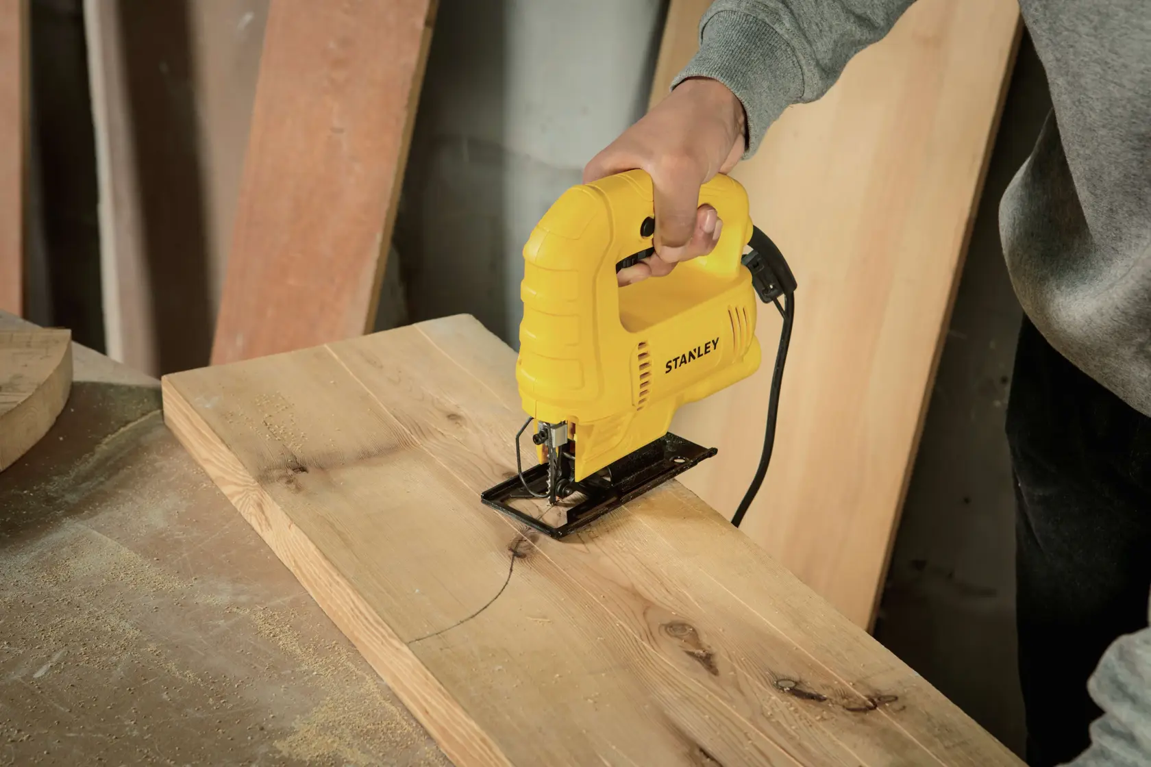 STANLEY SJ45 sierra caladora en uso cortando una línea curva en una tabla de madera en un taller.