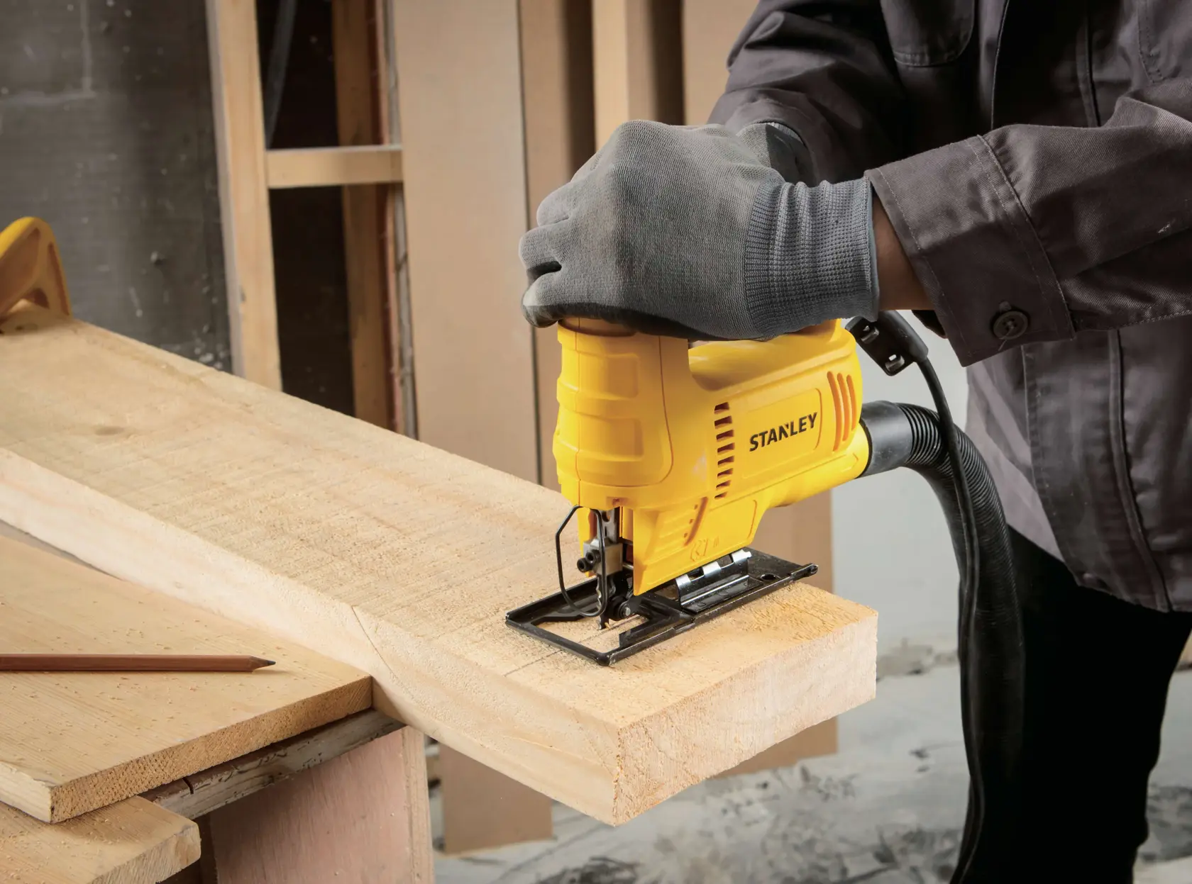 STANLEY SJ45 sierra caladora cortando madera, herramienta amarilla usada por mano enguantada en banco.