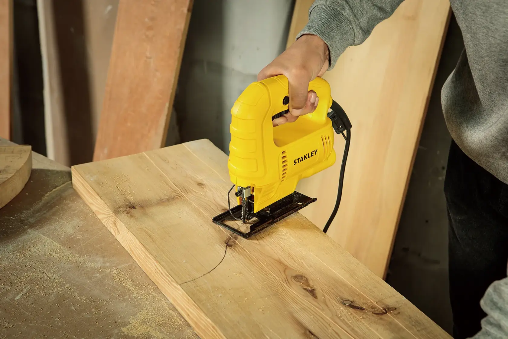 STANLEY SJ45 sierra caladora cortando línea curva en tabla de madera, primer plano de herramienta en uso.